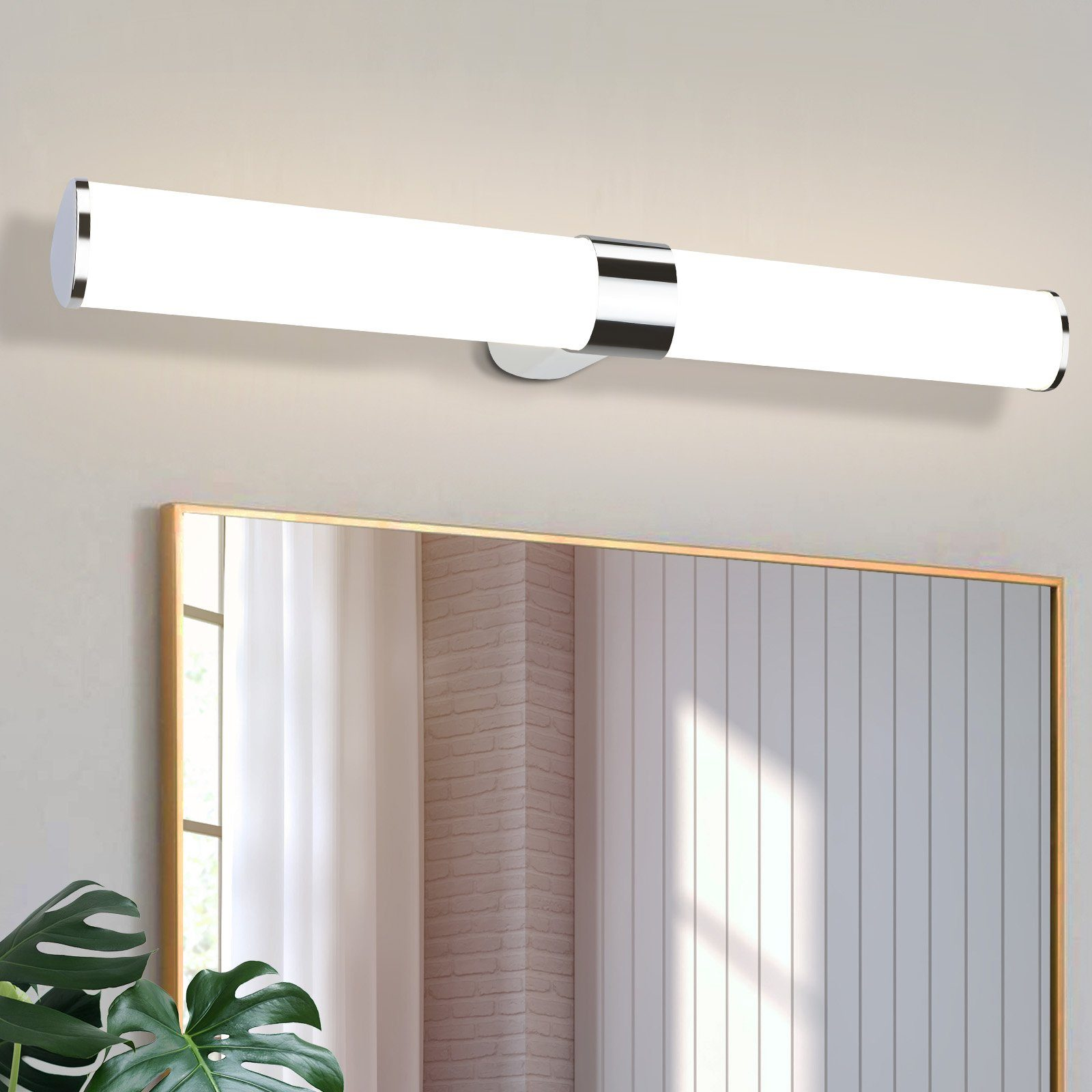 Specchio del bagno con un lungo e luminoso apparecchio sopra. L'apparecchio è argento e bianco. Una pianta nell'angolo.
