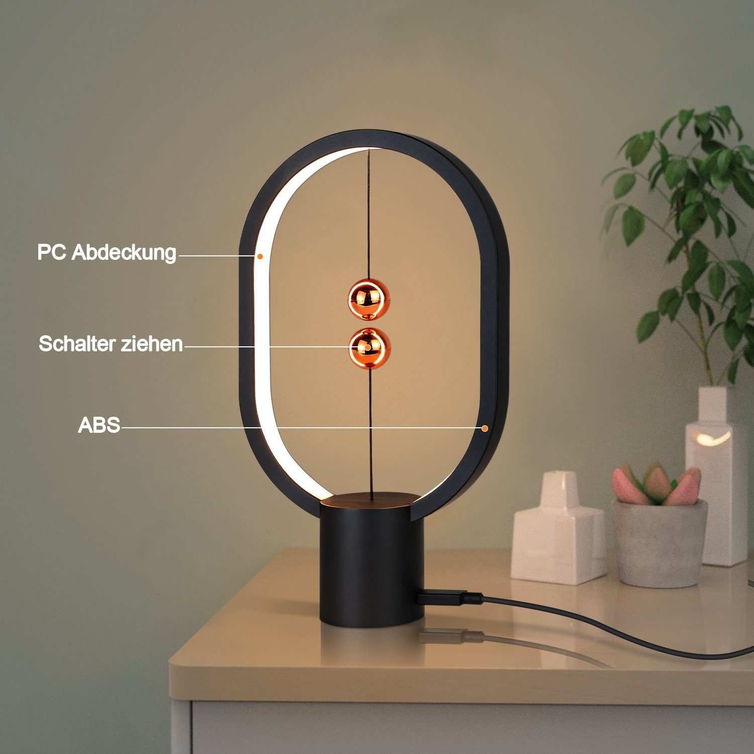 Czarna lampa z dwiema świecącymi kulami. Ma czarną podstawę. Na stole są przedmioty.