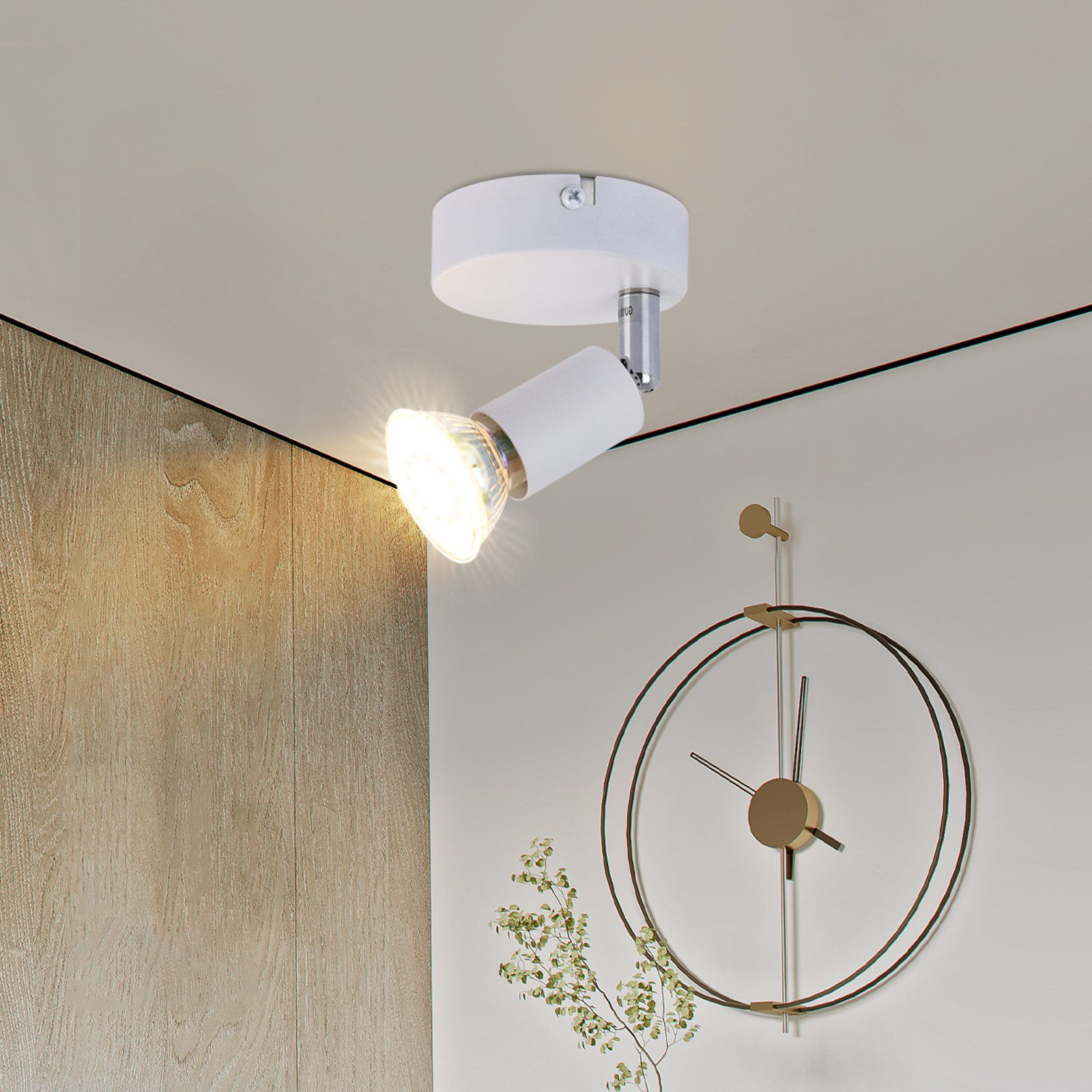 Faretto bianco con luce intensa sul soffitto, con una decorazione a orologio sullo sfondo.