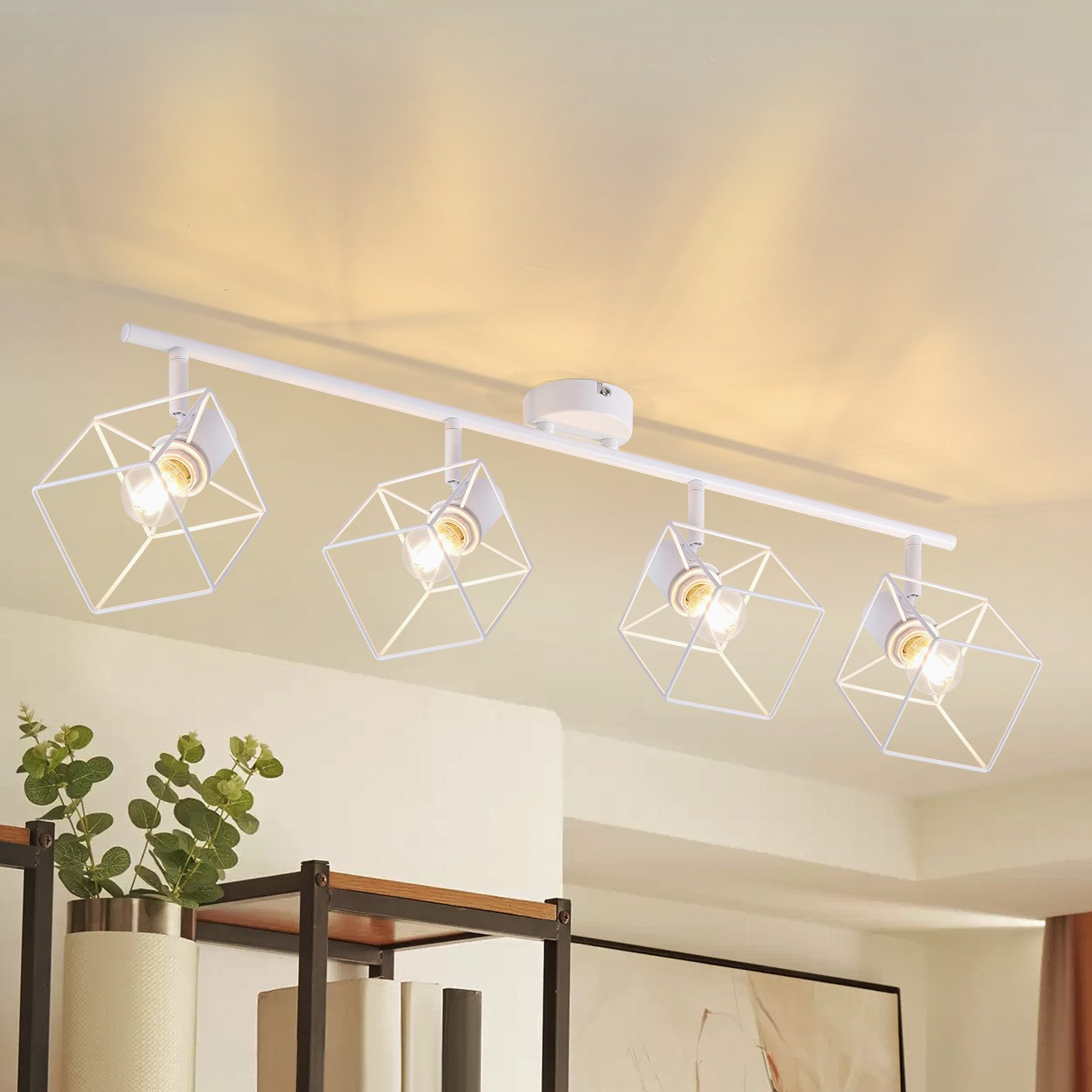 Lampada da soffitto bianca con quattro lampade. Ogni lampada ha una gabbia geometrica. Soffitto bianco. Piante sulla mensola.
