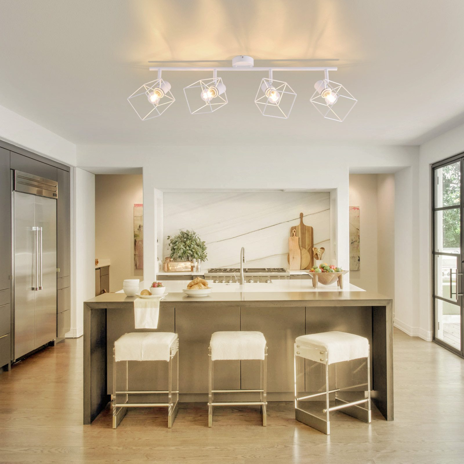 Cucina con luci geometriche bianche, un'isola grigia con tre sgabelli ed elettrodomestici in acciaio inox.