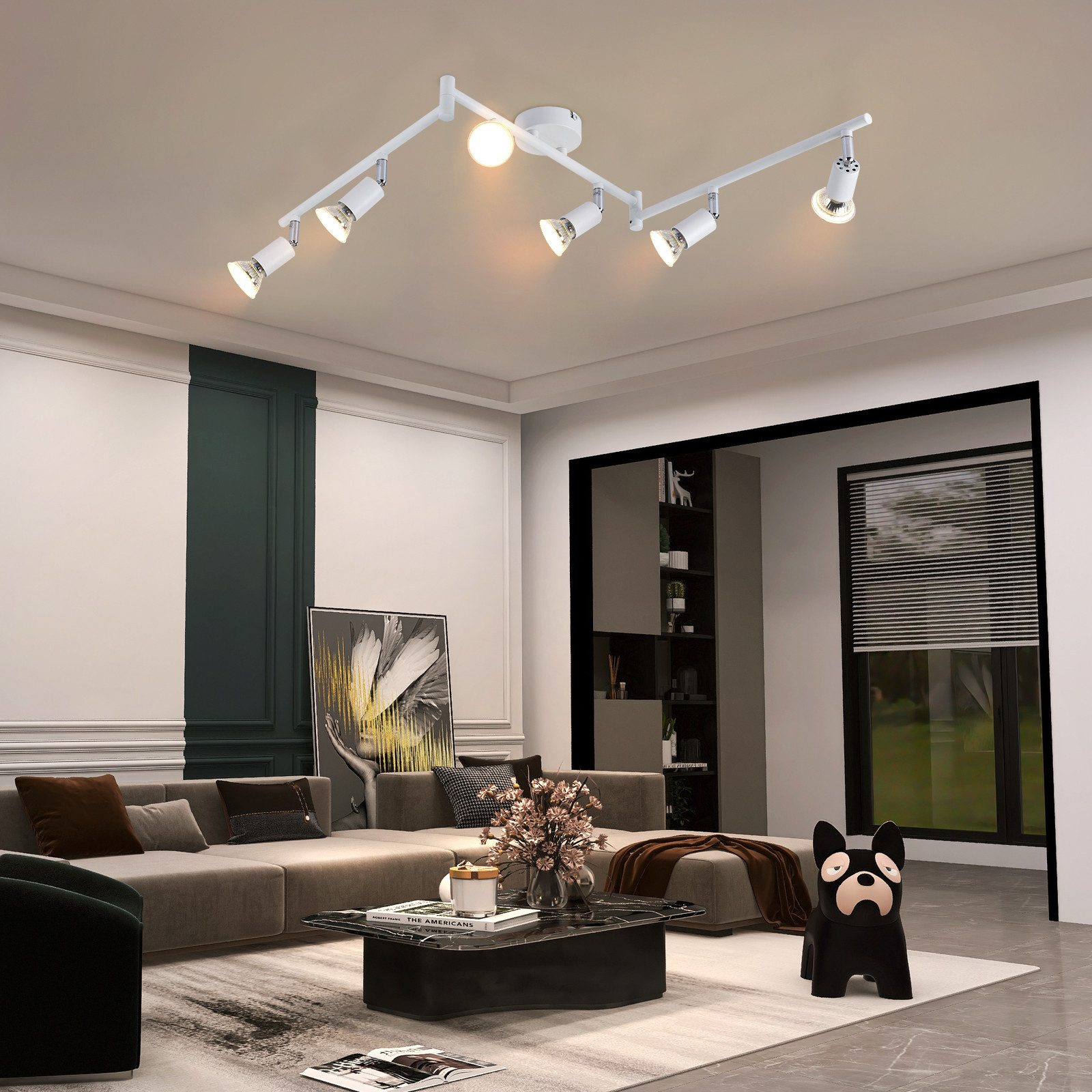 Un soggiorno moderno con soffitto bianco, illuminazione a binario e divano grigio. Una statua di cane nero è sul pavimento.