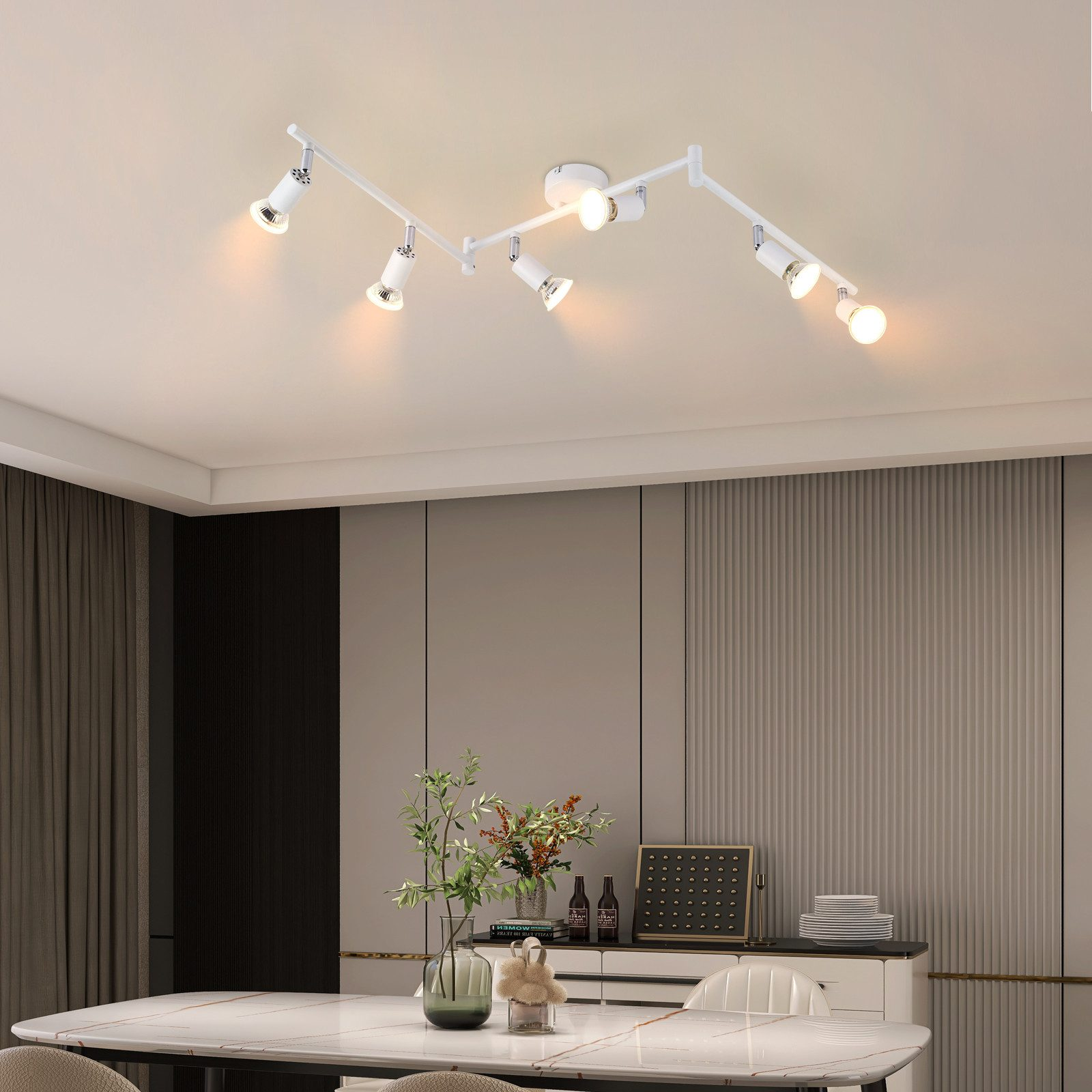 Un lampadario con faretti multipli. Un tavolo da pranzo con piante.