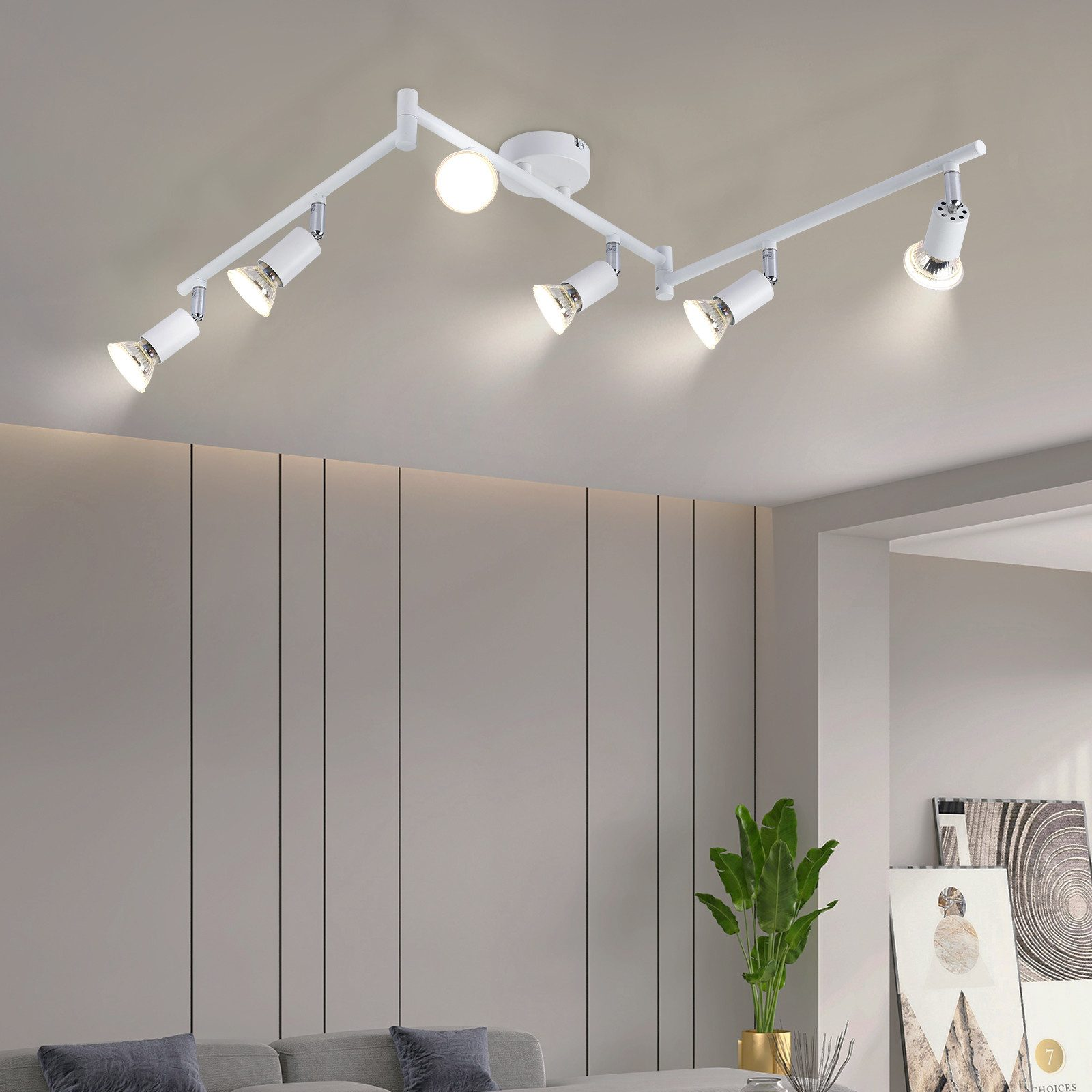 Illuminazione a binario da soffitto bianca con più faretti regolabili, che illumina un salotto moderno.