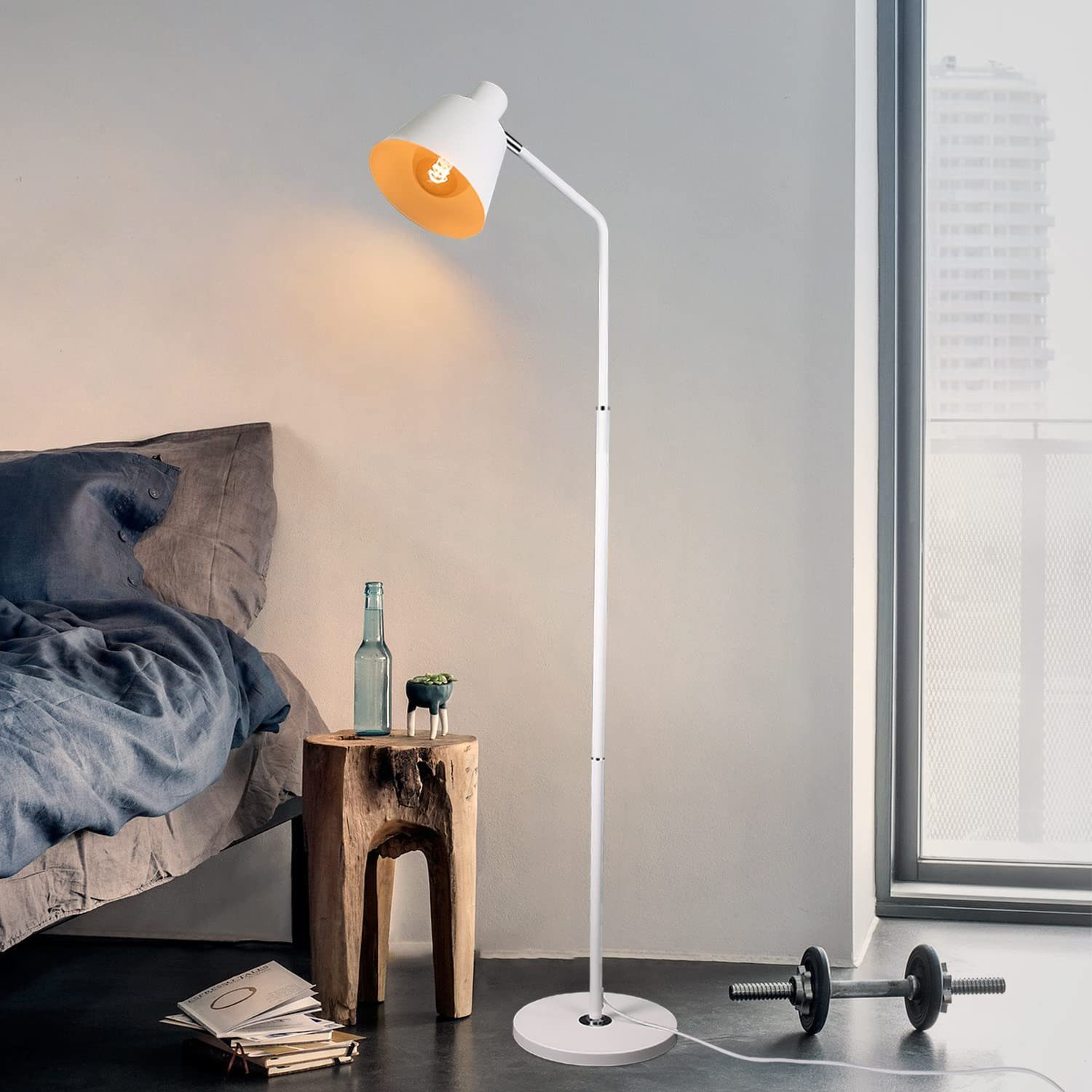 Eine weiße Stehlampe mit gelbem Innenraum, ein Holzschemel, eine Flasche und eine Hantel in einem Raum.