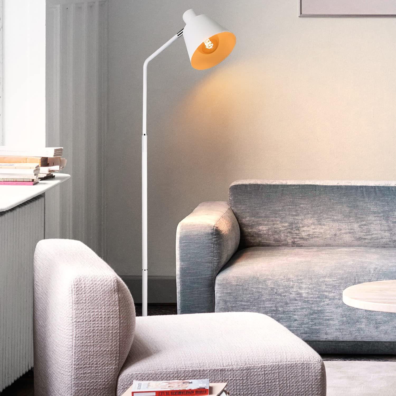 Weiße Stehlampe mit weißem und goldenem Schirm neben einem Sofa.
