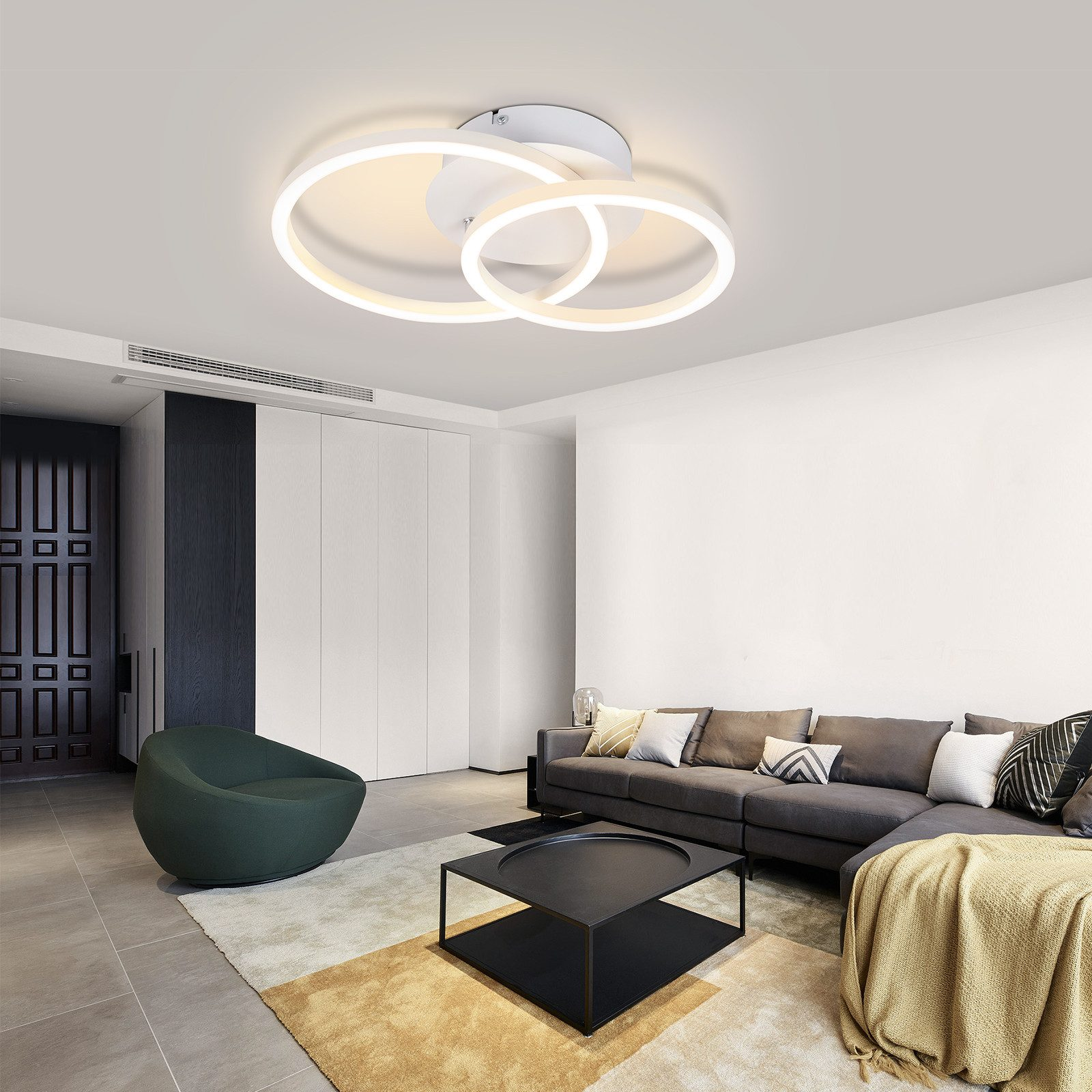 Soggiorno con pareti bianche, divano grigio, tavolino nero e lampada da soffitto.