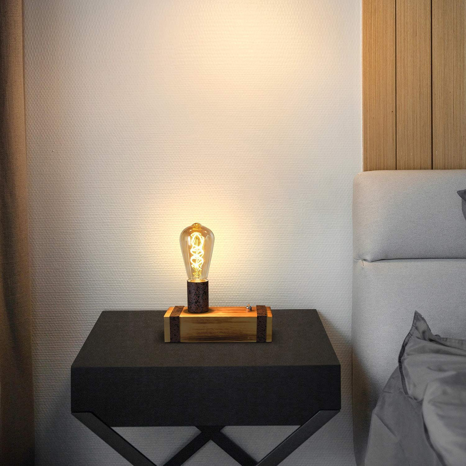 Świecąca żarówka na czarnym stoliku nocnym obok łóżka.
