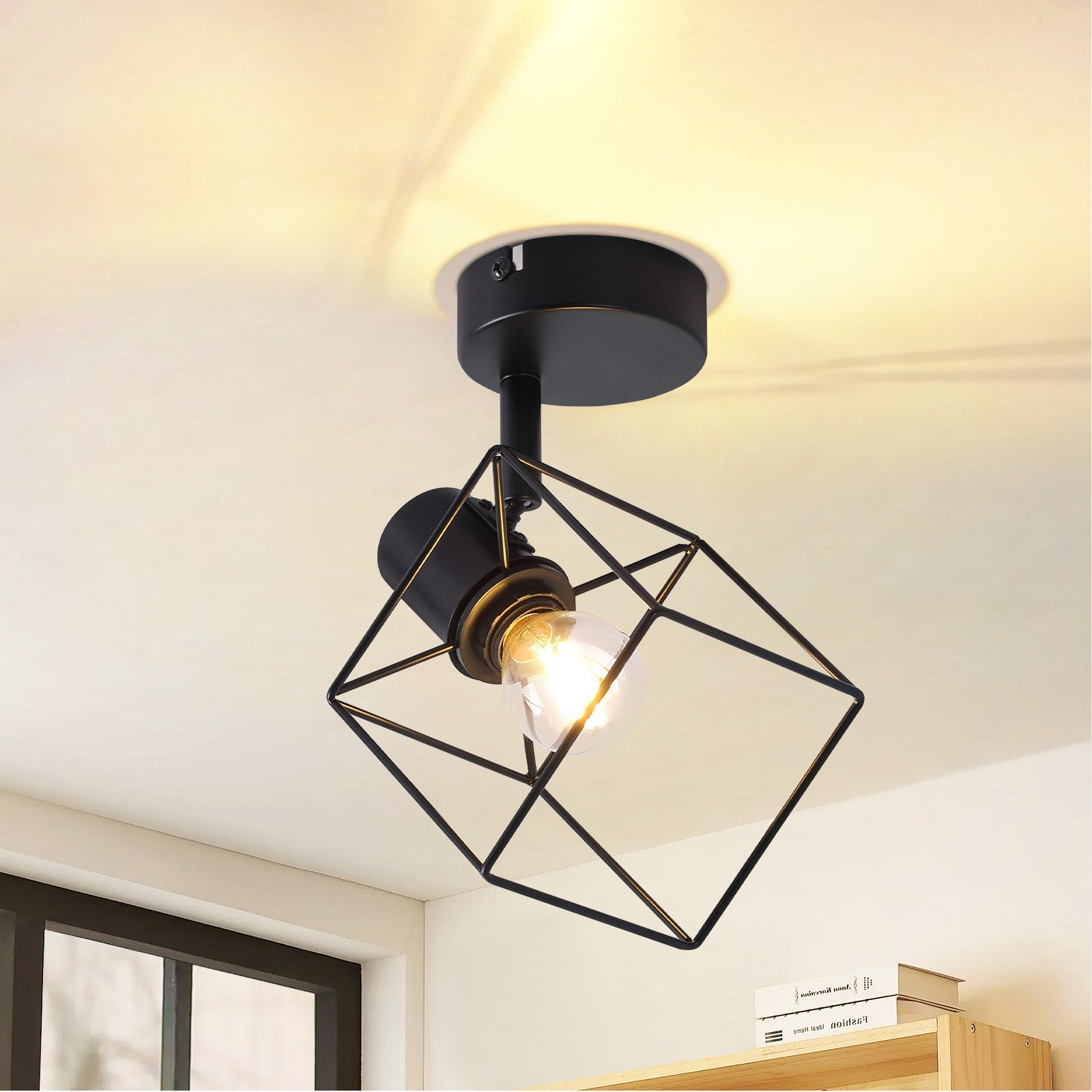 Lampada da soffitto nera con gabbia geometrica attorno alla lampadina. Soffitto bianco.