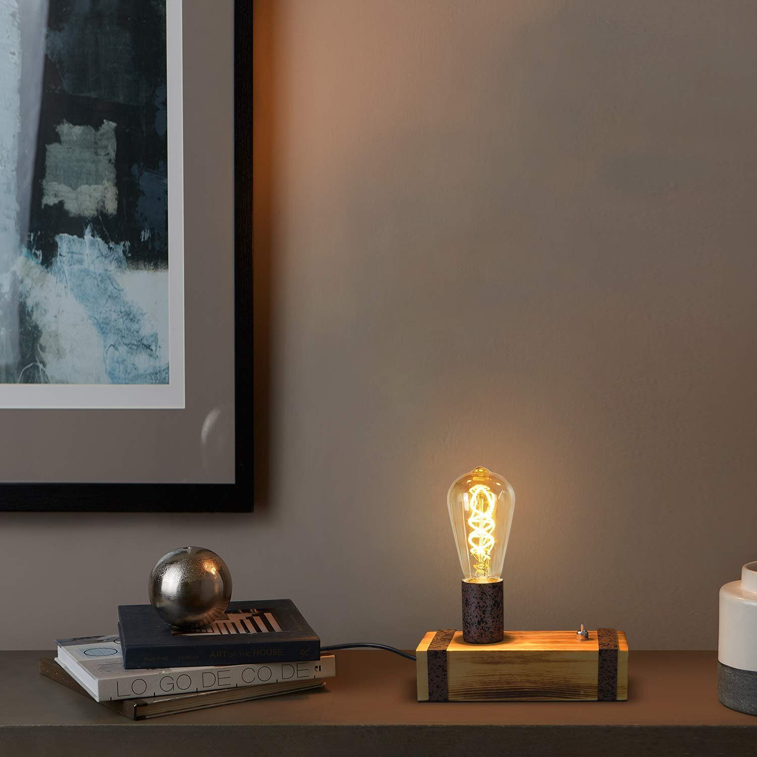 Podświetlona żarówka Edisona na drewnianej podstawie z czarnym kablem, srebrną kulą i książką.