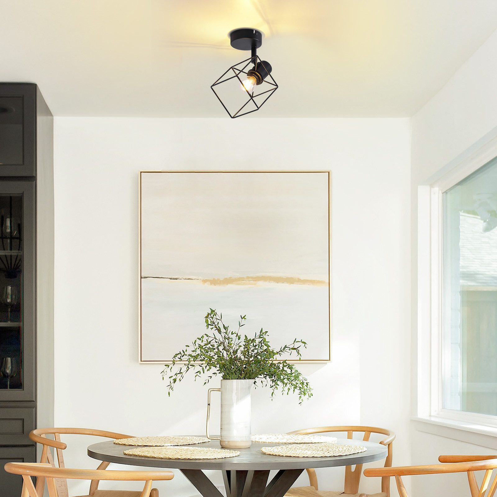 Un apparecchio nero, in stile gabbia geometrica, che illumina una zona pranzo.
