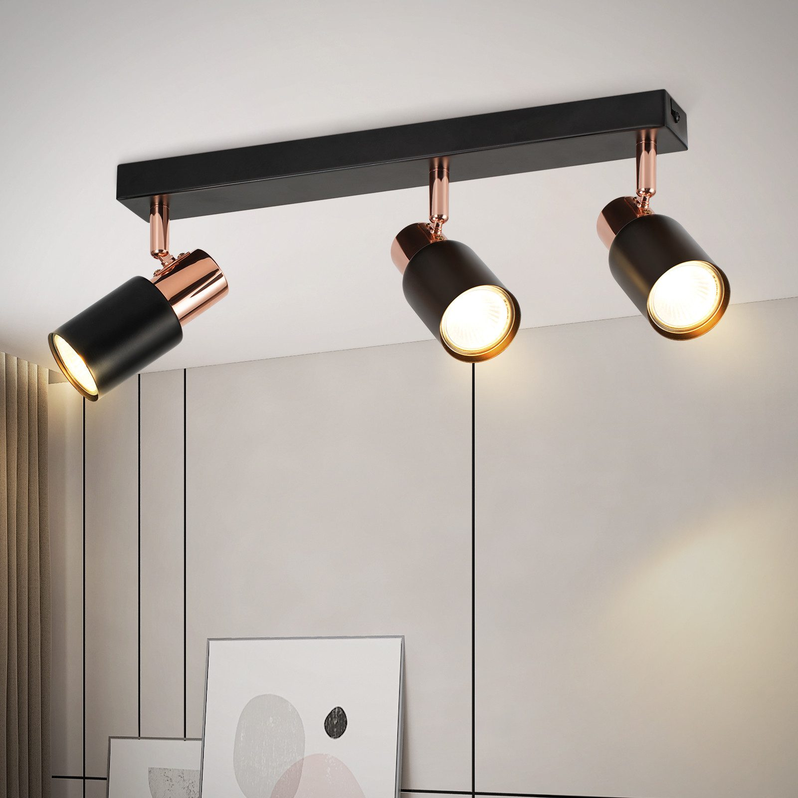 Faretti neri con accenti ramati su un soffitto bianco. Sono visibili tre luci, che brillano verso il basso. Lo sfondo è bianco.