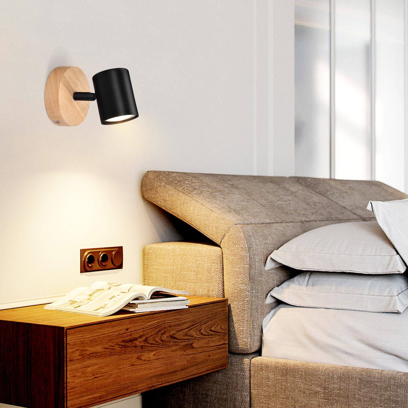 Un faretto a parete con testa della lampada nera e base in legno, che illumina un comodino.