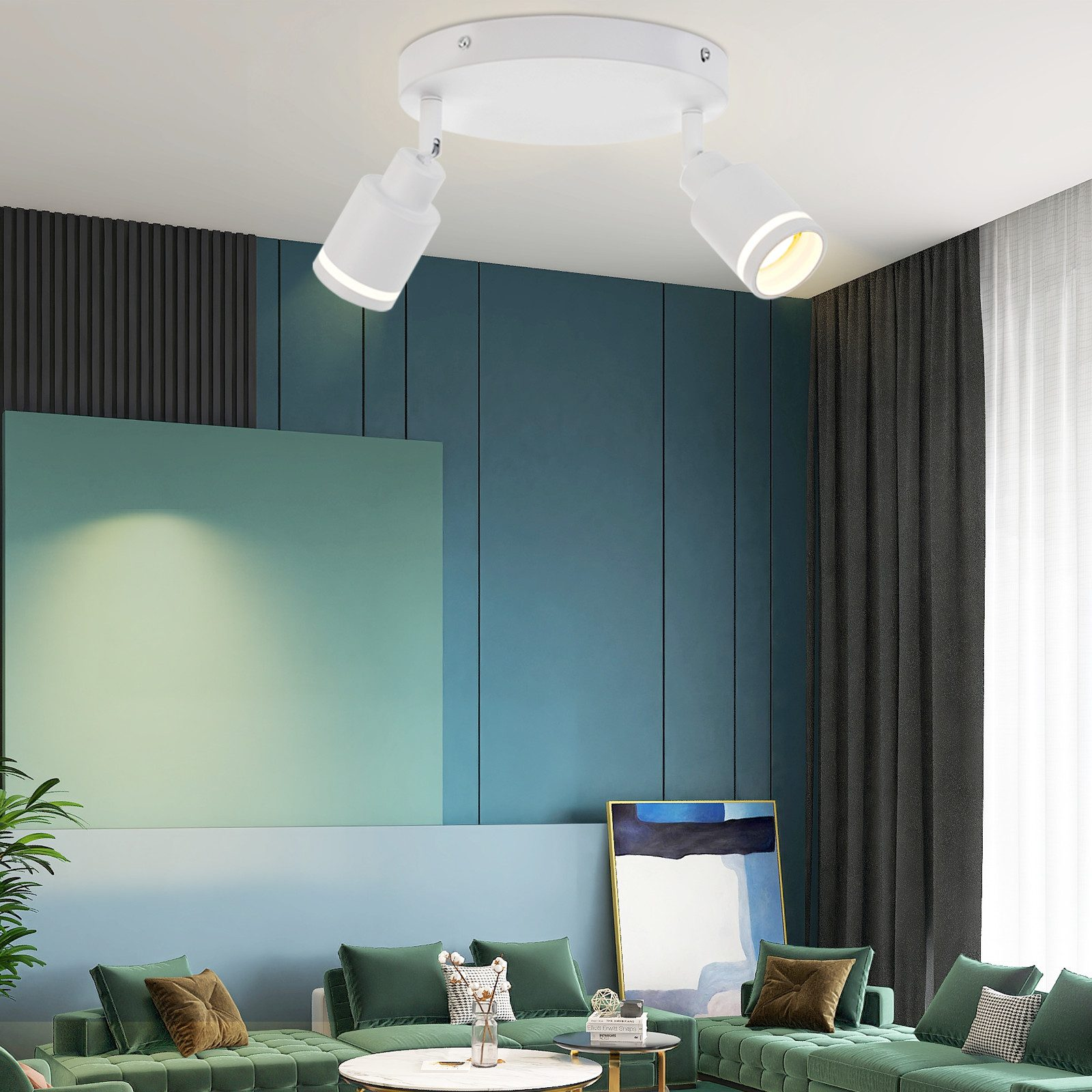 Due faretti bianchi su un soffitto bianco. Puntano in direzioni diverse. Un divano e un dipinto sono nella stanza.