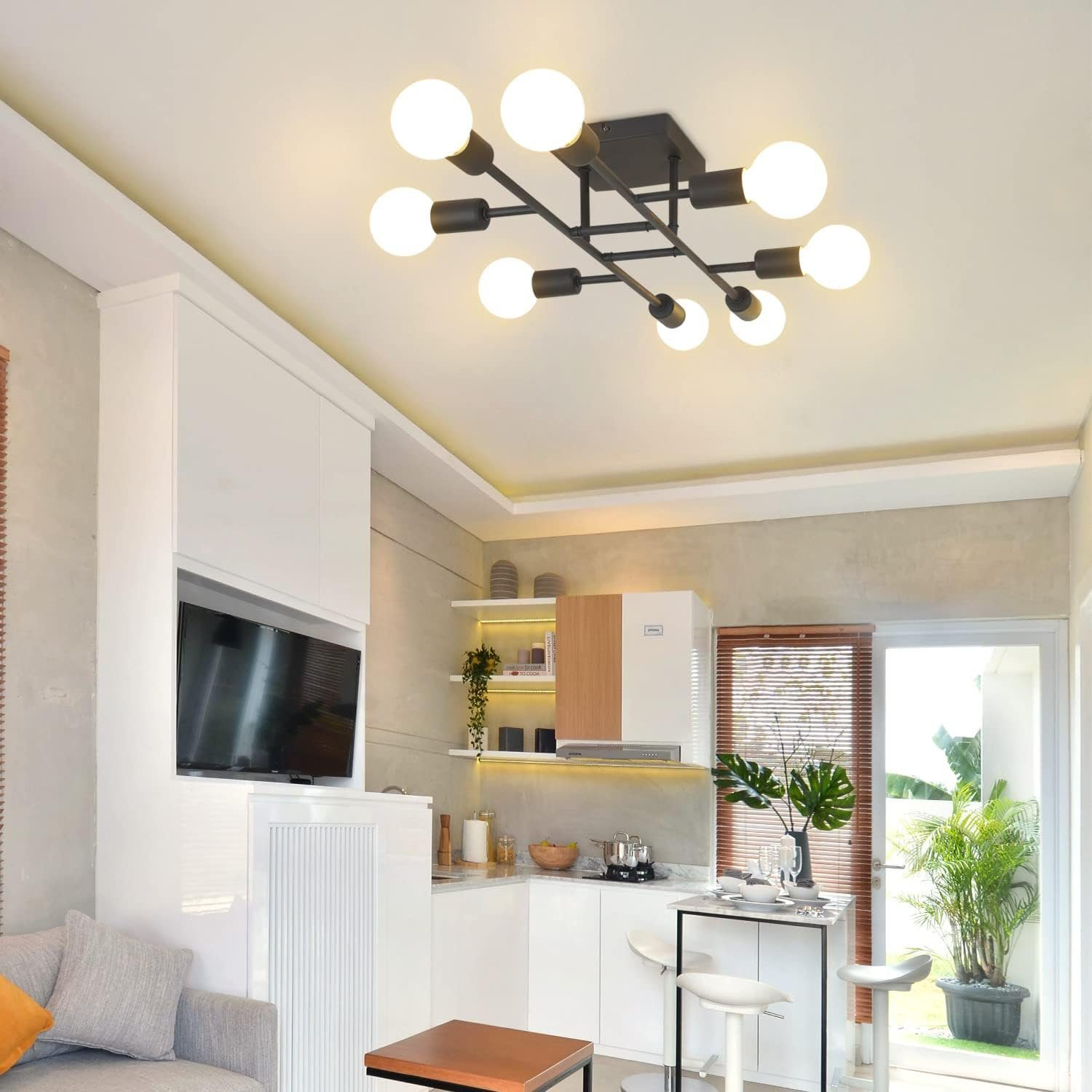 Cucina moderna con lampada da soffitto nera con otto lampadine a globo. Armadietti bianchi e un'isola piccola.