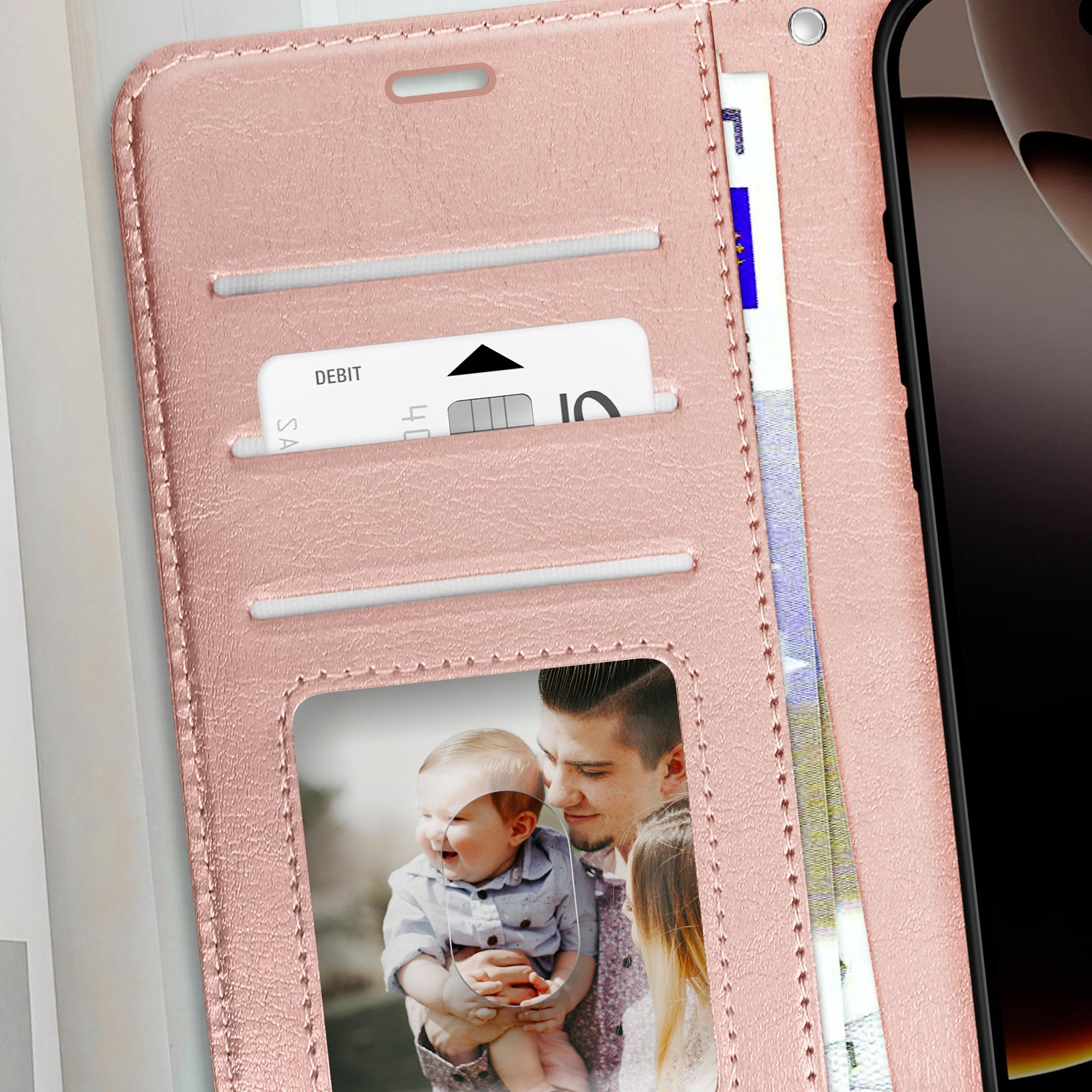 Una custodia per telefono rosa aperta con una foto di famiglia e una carta di debito, su sfondo bianco.