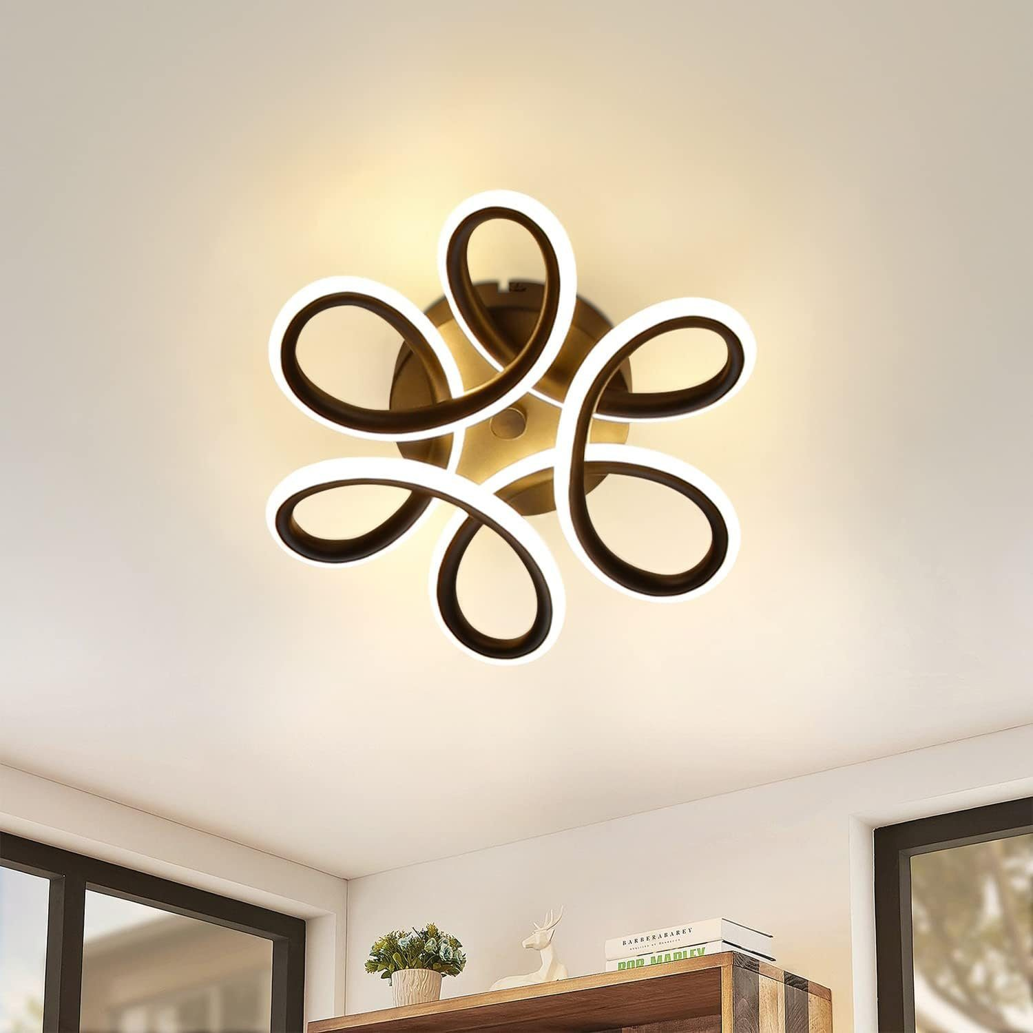 Una moderna plafoniera con un design floreale. Ha una base in bronzo e luce bianca.