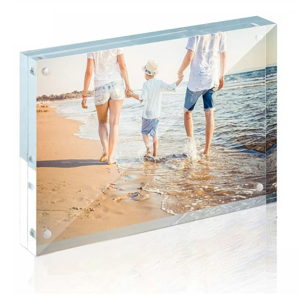 Eine dreiköpfige Familie geht am Strand entlang. Sie halten Händchen. Das Bild ist in einem klaren Rahmen.