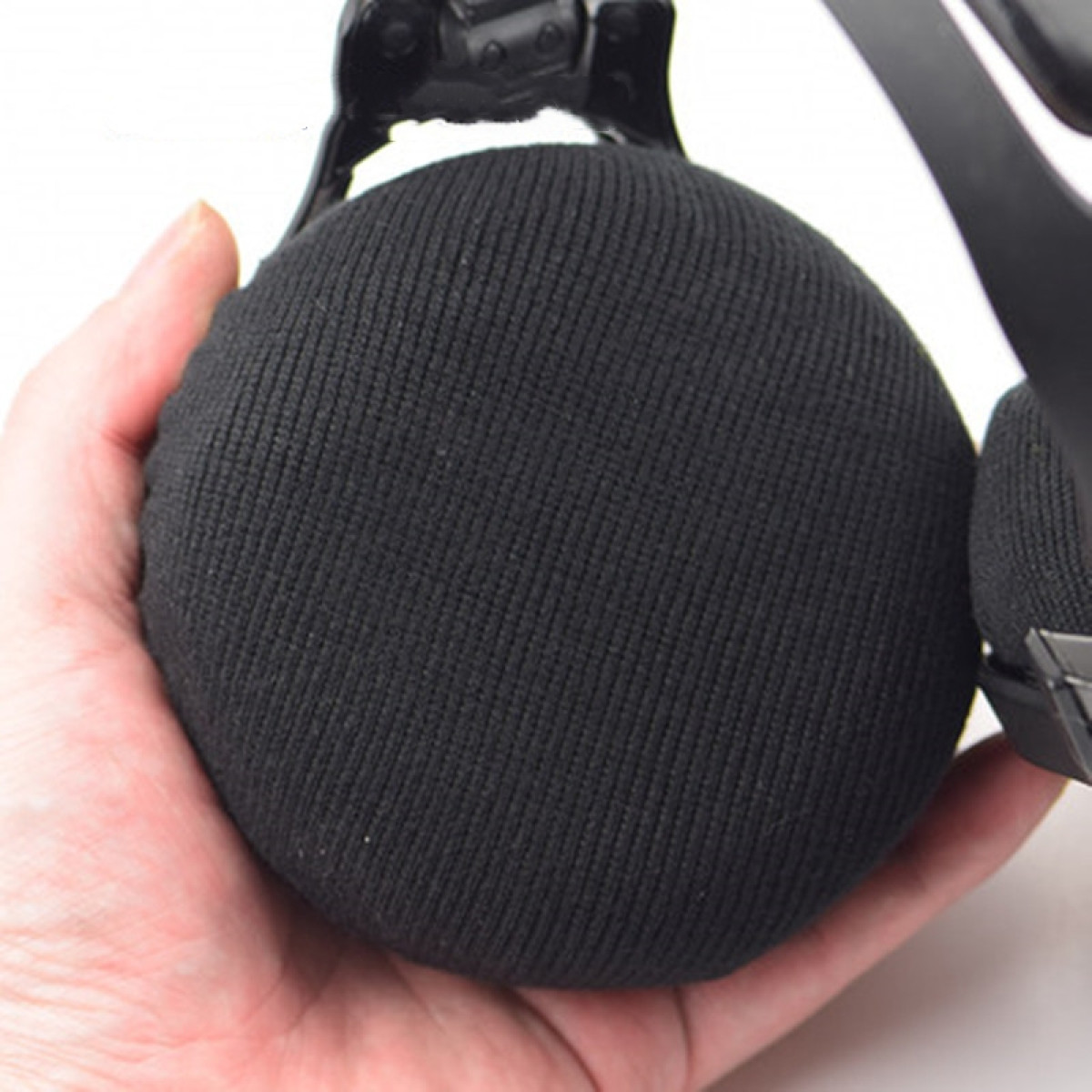 Hand hält schwarzen, runden, stoffbezogenen Ohrmuschel eines Headsets.