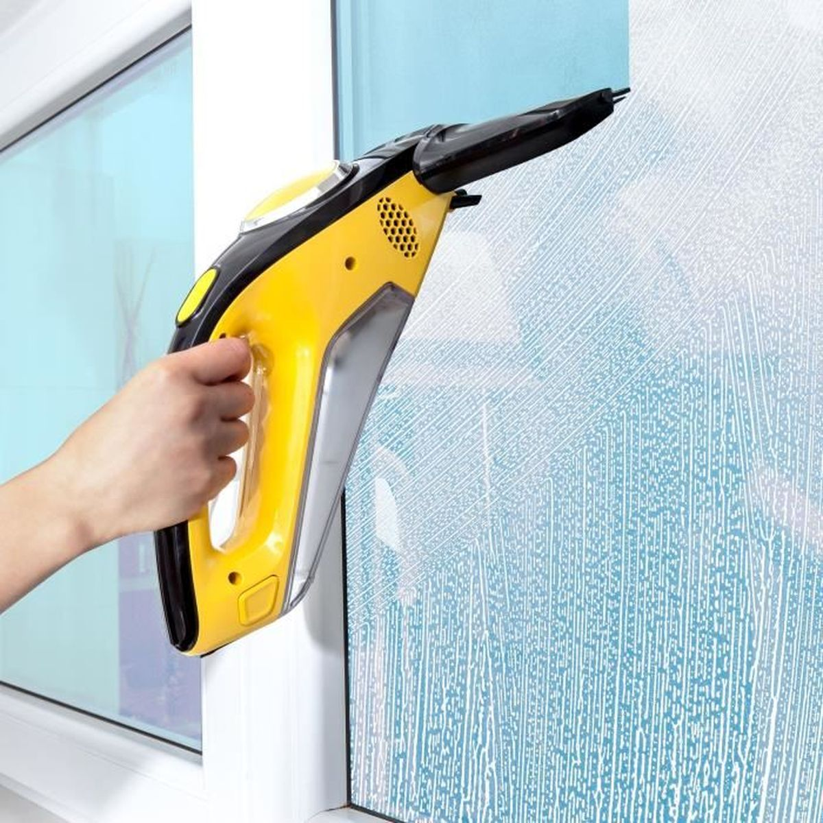 Eine Hand benutzt einen gelben Fensterreiniger. Seife auf dem Fenster. Draußen ist blau.