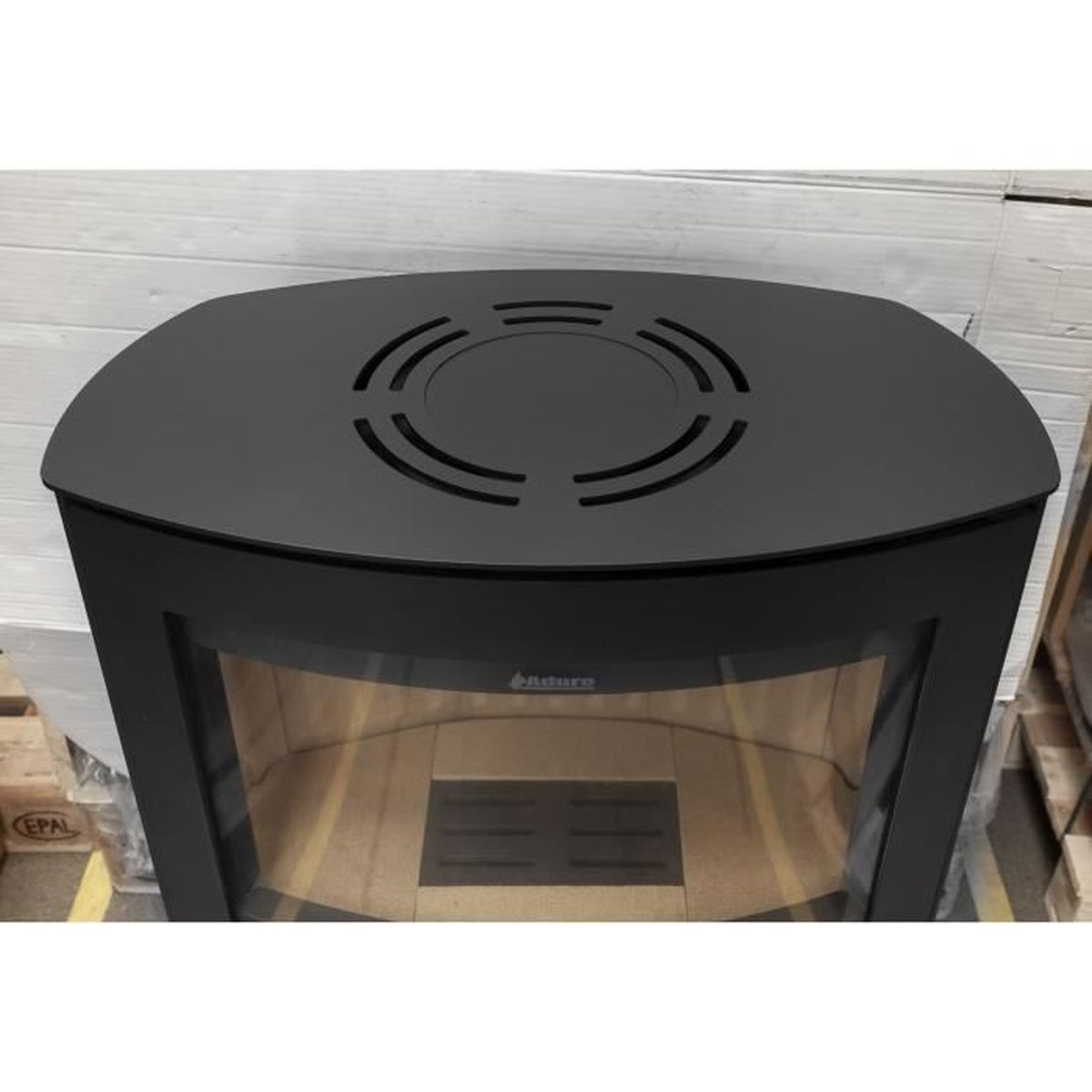 Ein schwarzer Metallkaminaufsatz mit Lüftungslöchern. Der Kamin befindet sich in einer Holzkiste.