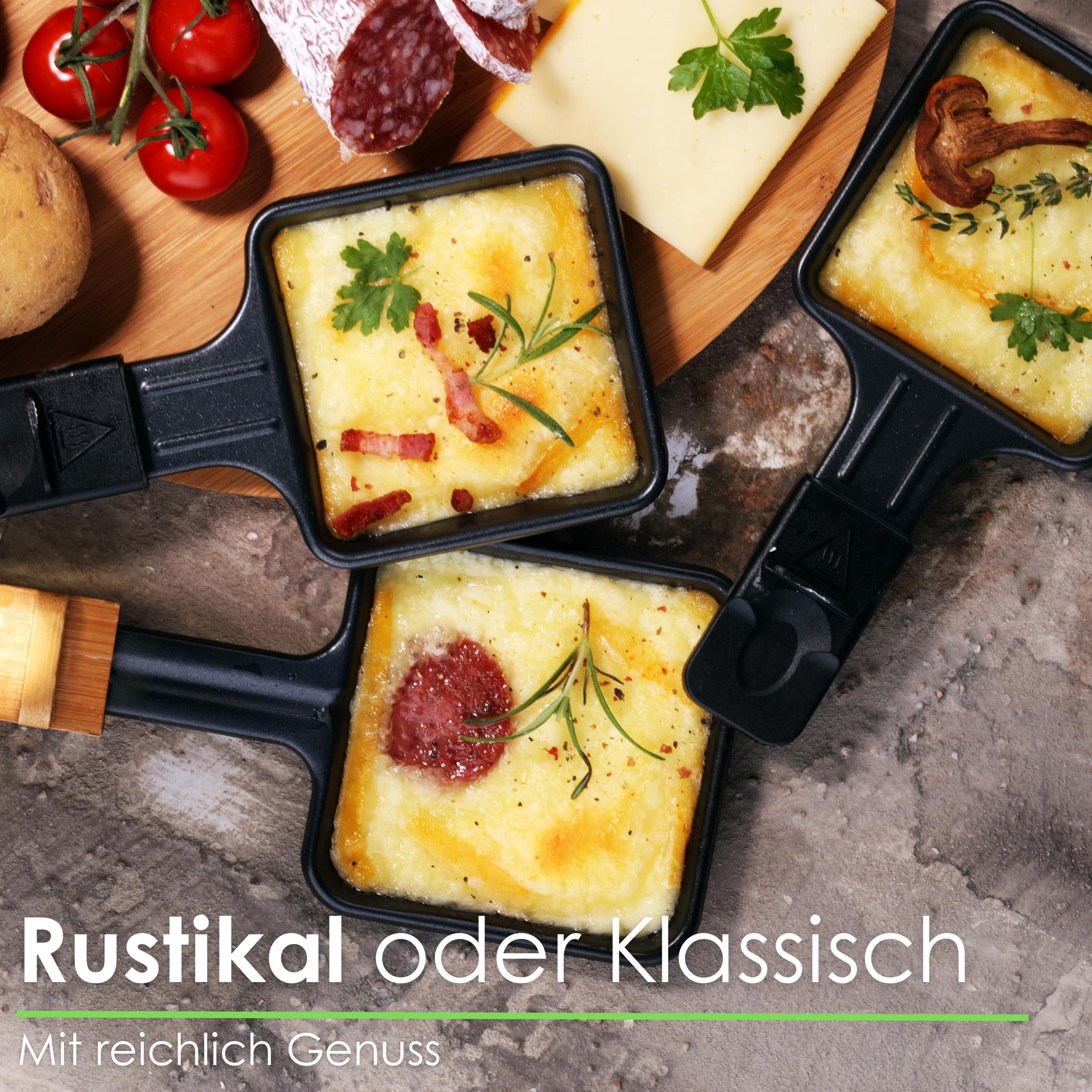 Raclette-Pfannen mit geschmolzenem Käse, Speck und Kräutern. Salami, Tomaten, Käse und eine Kartoffel sind ebenfalls abgebildet.