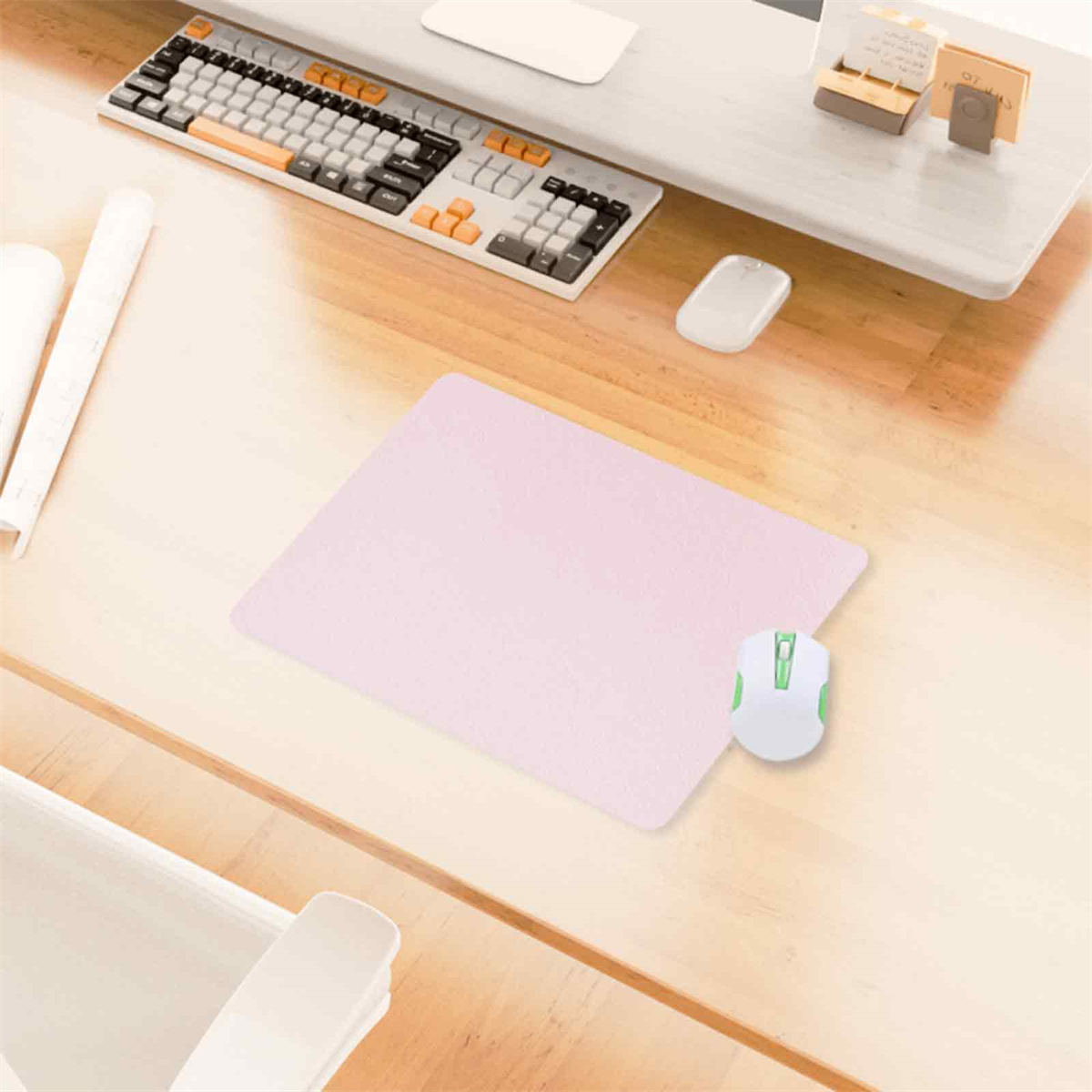 Rosa Mauspad mit einer weißen Maus. Eine Tastatur ist im Hintergrund.