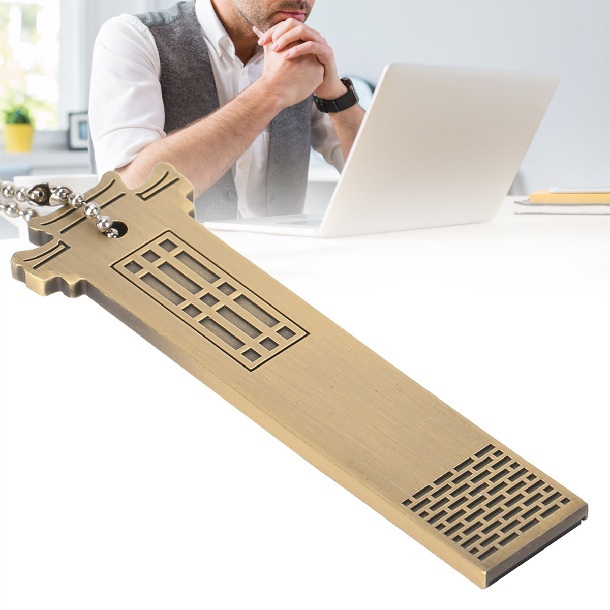 Ein goldfarbener USB-Stick auf einem Tisch. Im Hintergrund denkt ein Mann vor einem Laptop.
