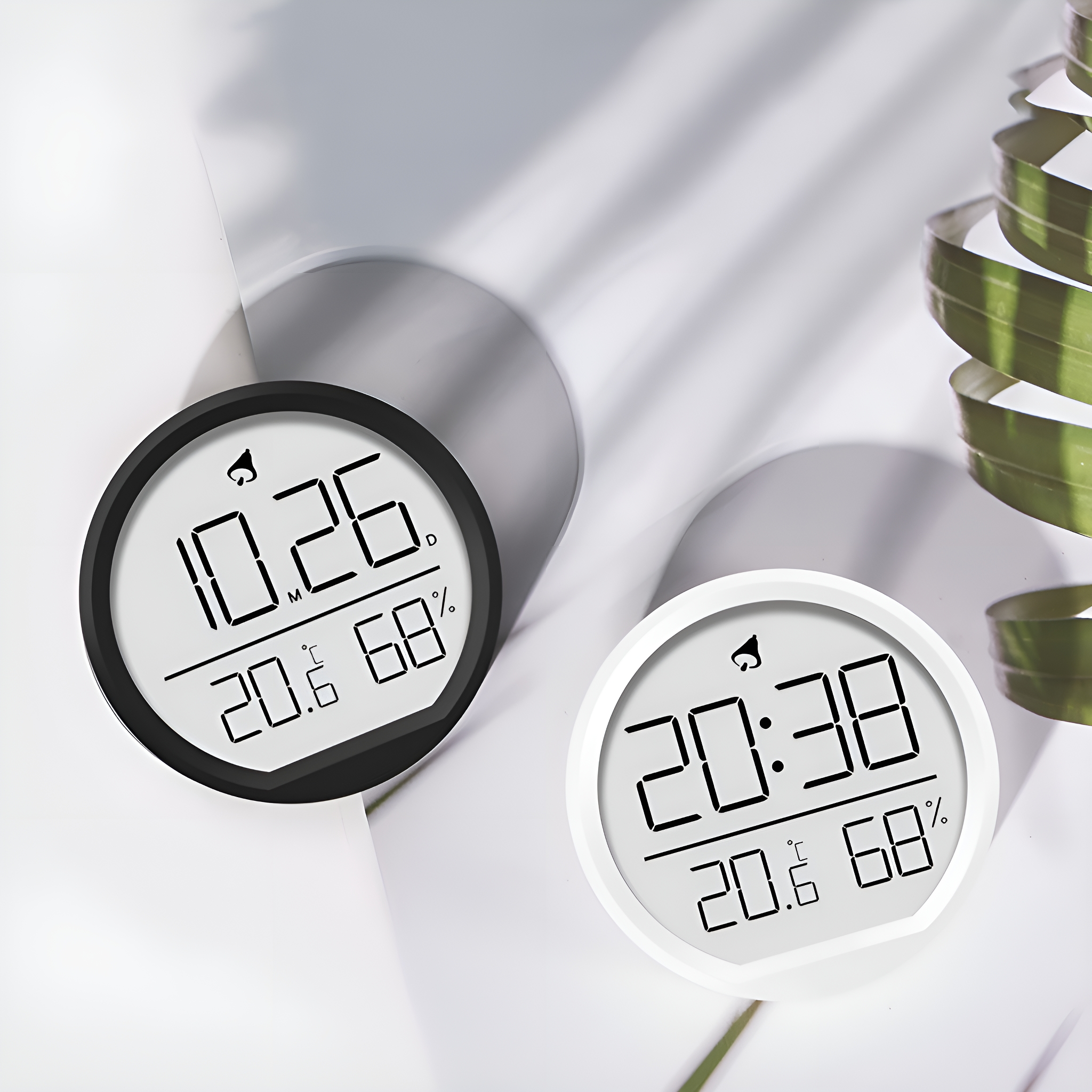 Zwei digitale Thermometer, schwarz und weiß, zeigen Zeit und Temperatur an.