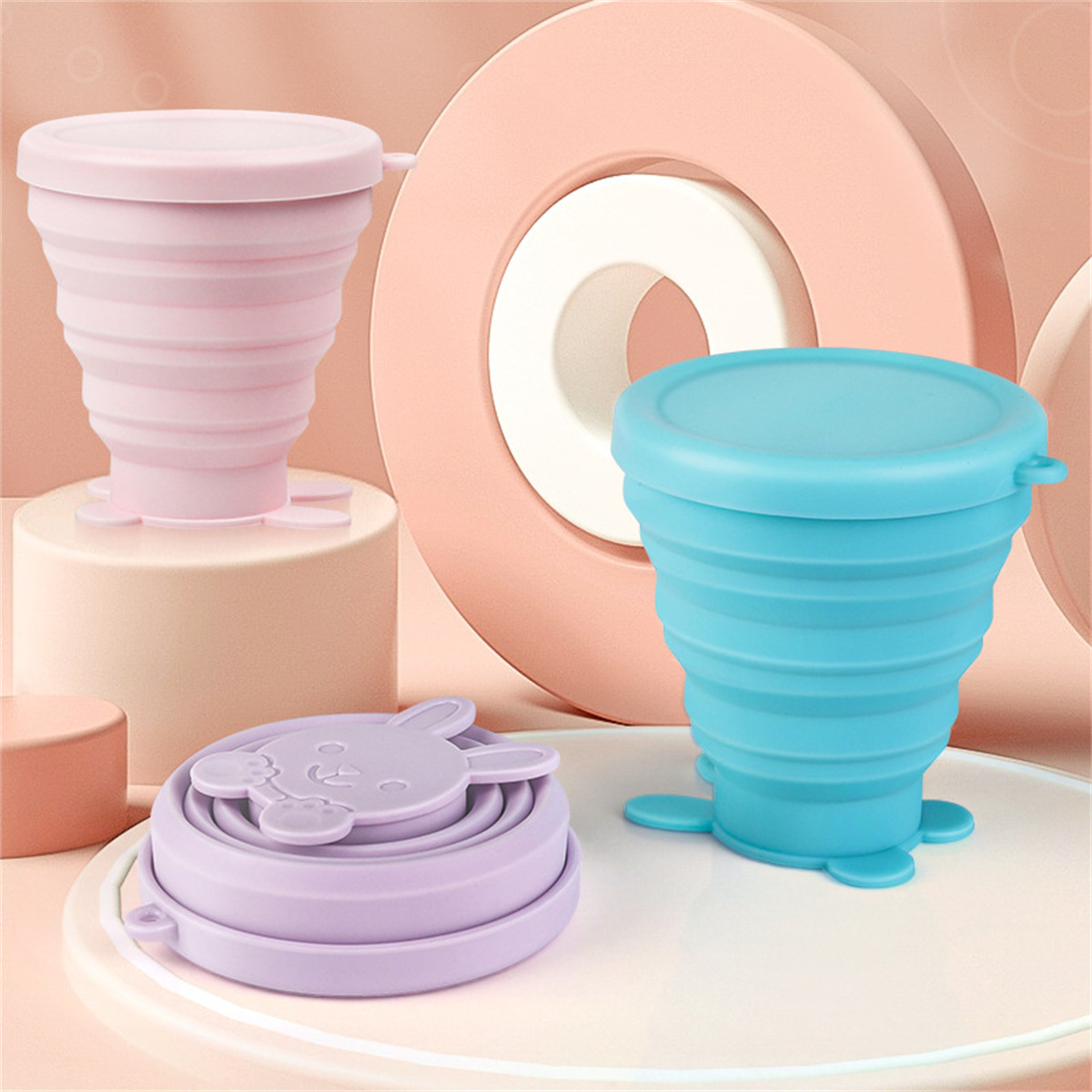 Zusammenklappbare, wiederverwendbare Becher in drei Farben: Rosa, Blau und Lila. Die Becher bestehen aus Silikon.
