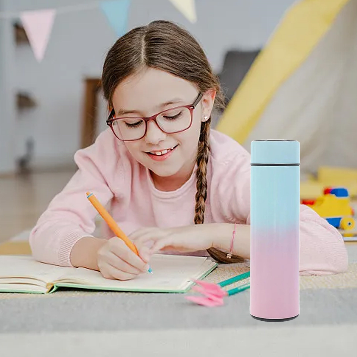 Mädchen schreibt in ein Notizbuch, mit einer rosa und blau verlaufenden Wasserflasche in der Nähe.