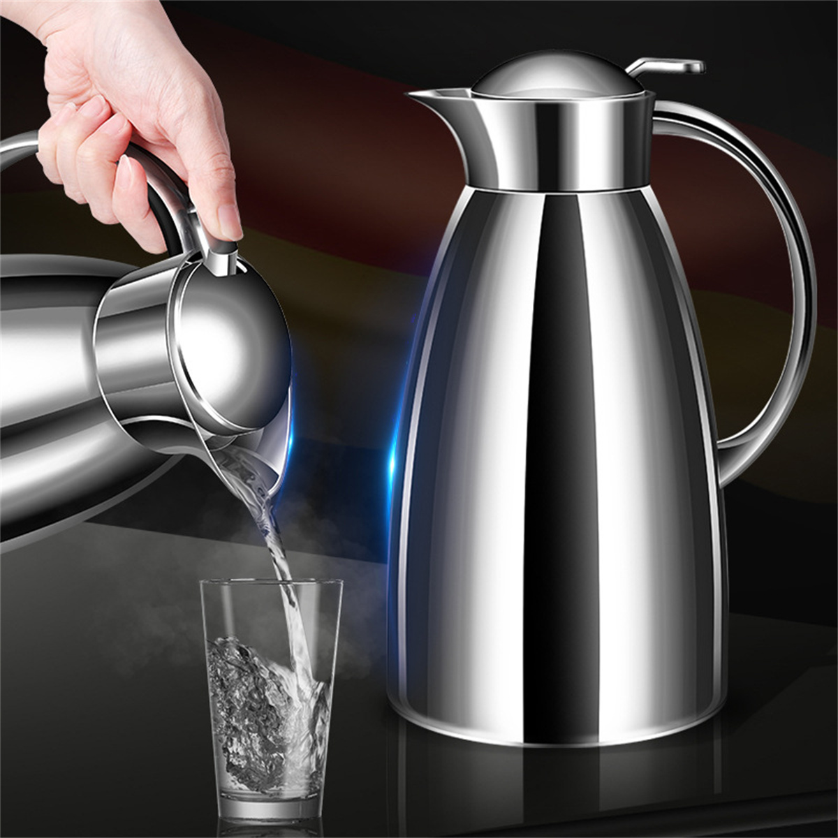 Eine Hand gießt Wasser aus einer silbernen Karaffe in ein Glas. Eine weitere Karaffe steht daneben.
