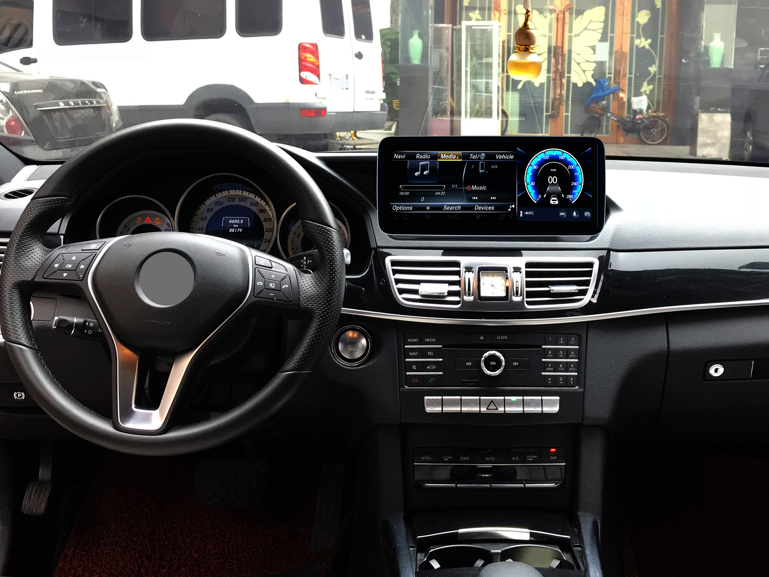 Armaturenbrett eines Autos mit einem Bildschirm mit Musik-, Medien- und Fahrzeuginformationen. Lenkrad sichtbar.