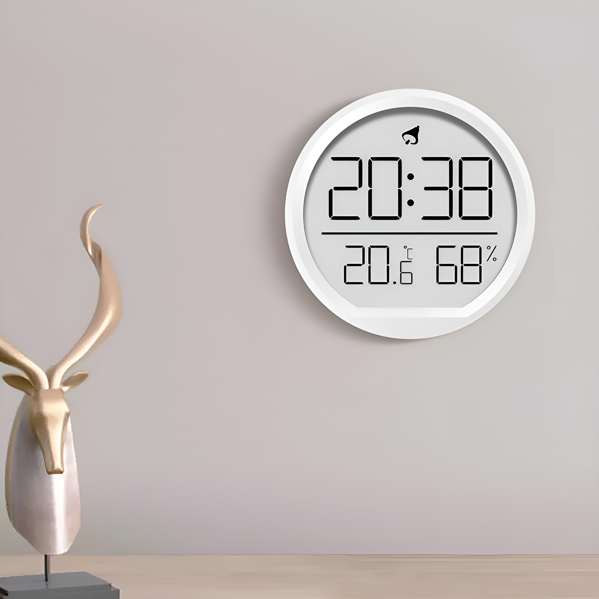 Eine weiße Digitaluhr an der Wand. Sie zeigt Zeit, Temperatur und Luftfeuchtigkeit. Goldene Hirschstatue.
