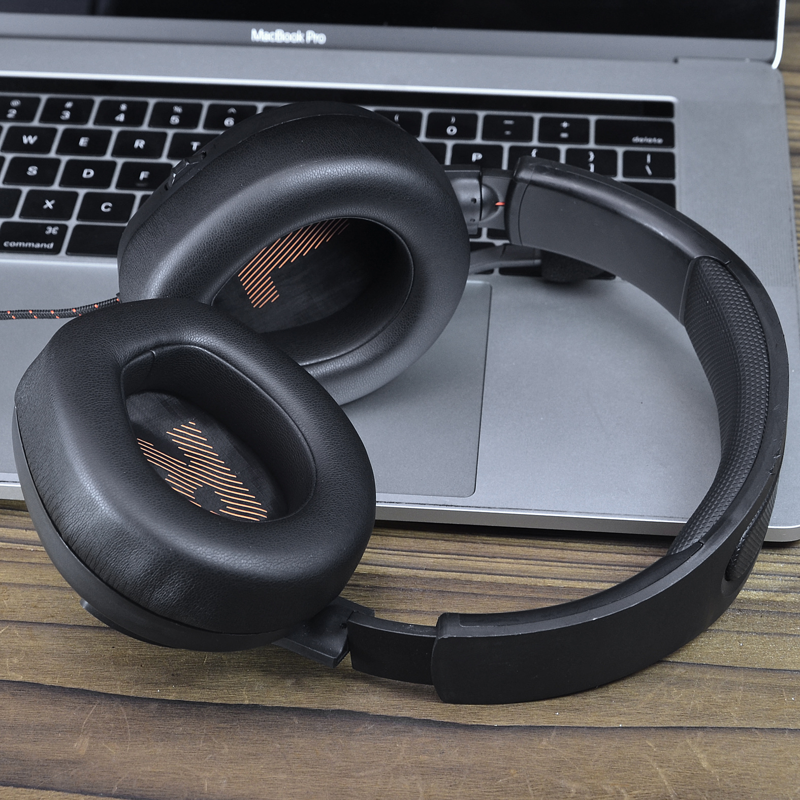 Czarne słuchawki na klawiaturze laptopa, z tłem drewnianej powierzchni.