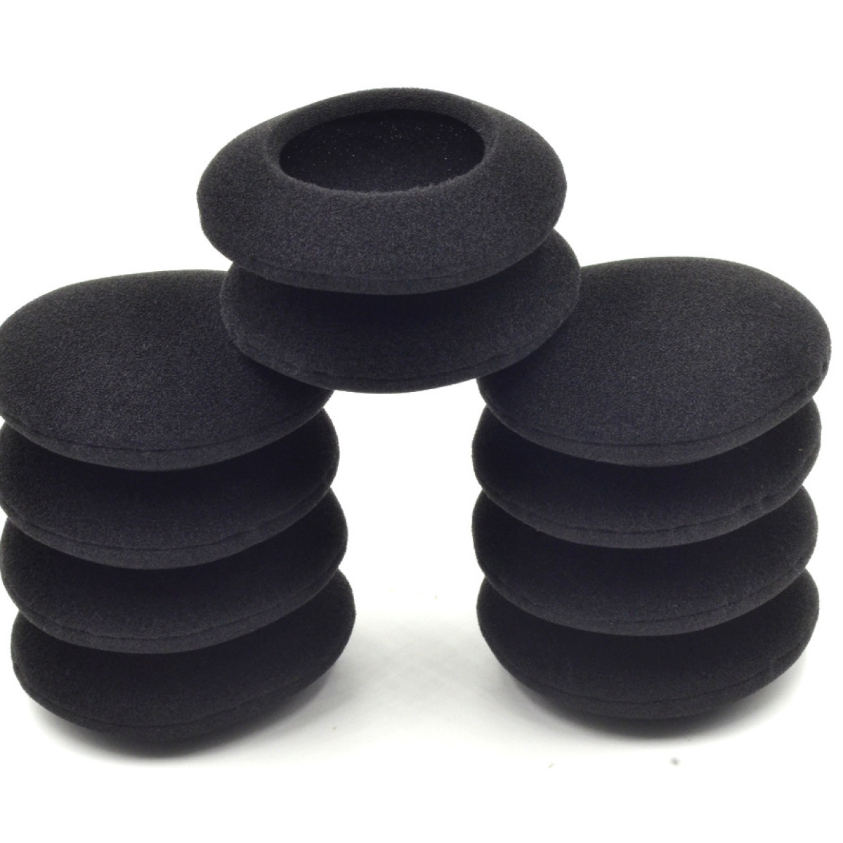 Kilka czarnych poduszek nausznych na białym tle. Ułożone w stos.