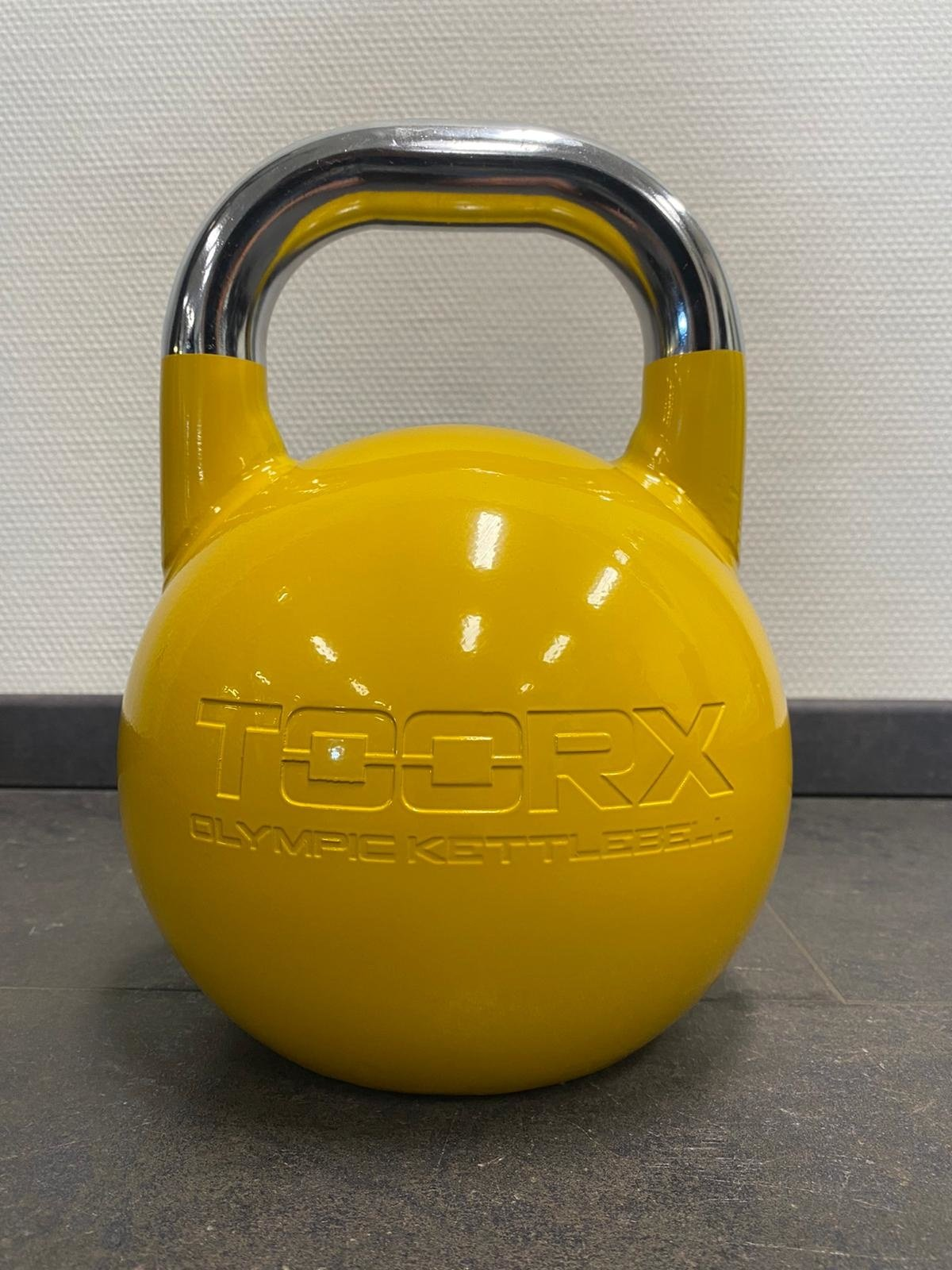 Eine gelbe Kettlebell mit silbernem Griff, dem Wort 'TOORX' und 'OLYMPIC KETTLEBELL'.