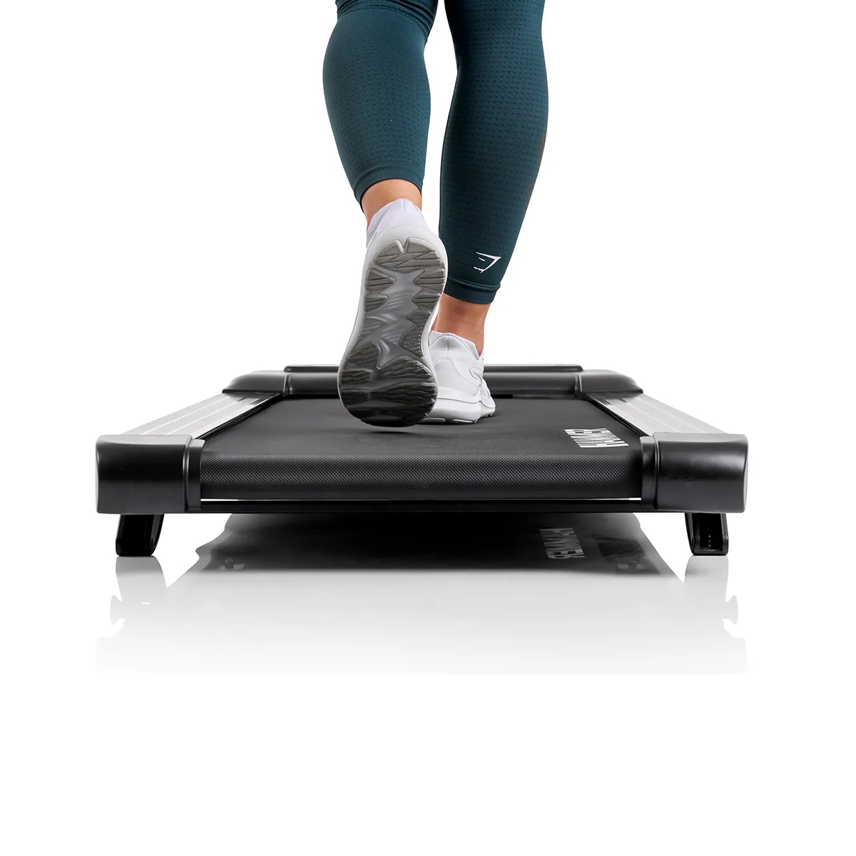 Eine Person, die auf einem schwarzen Laufband geht, trägt weiße Schuhe und türkisfarbene Leggings.