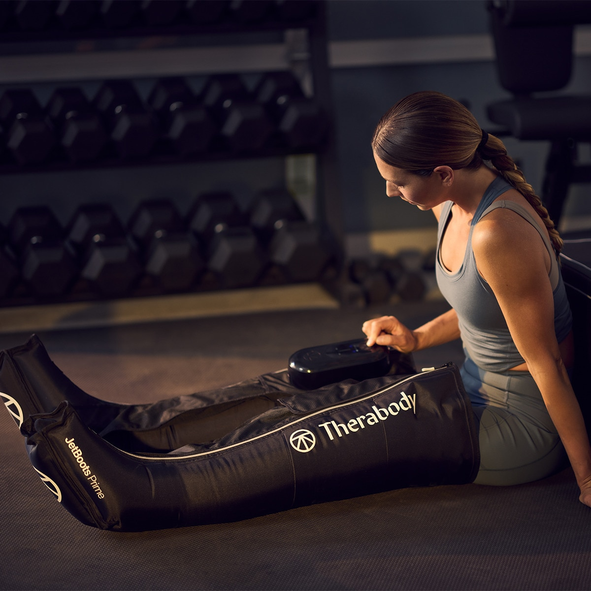 Mujer usando un dispositivo de compresión de piernas en el gimnasio.