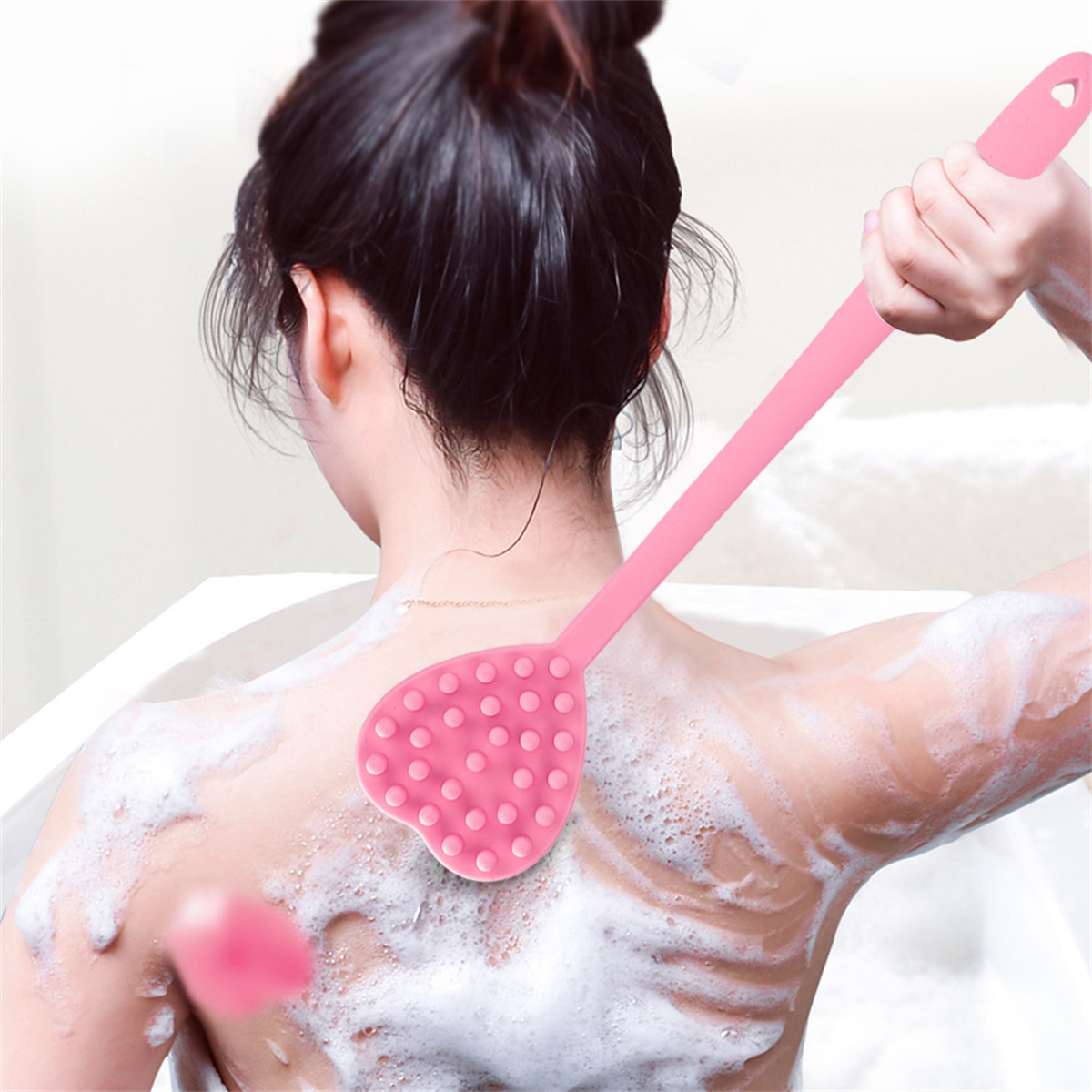 Eine Frau benutzt einen rosa Rückenschrubber mit langem Griff.