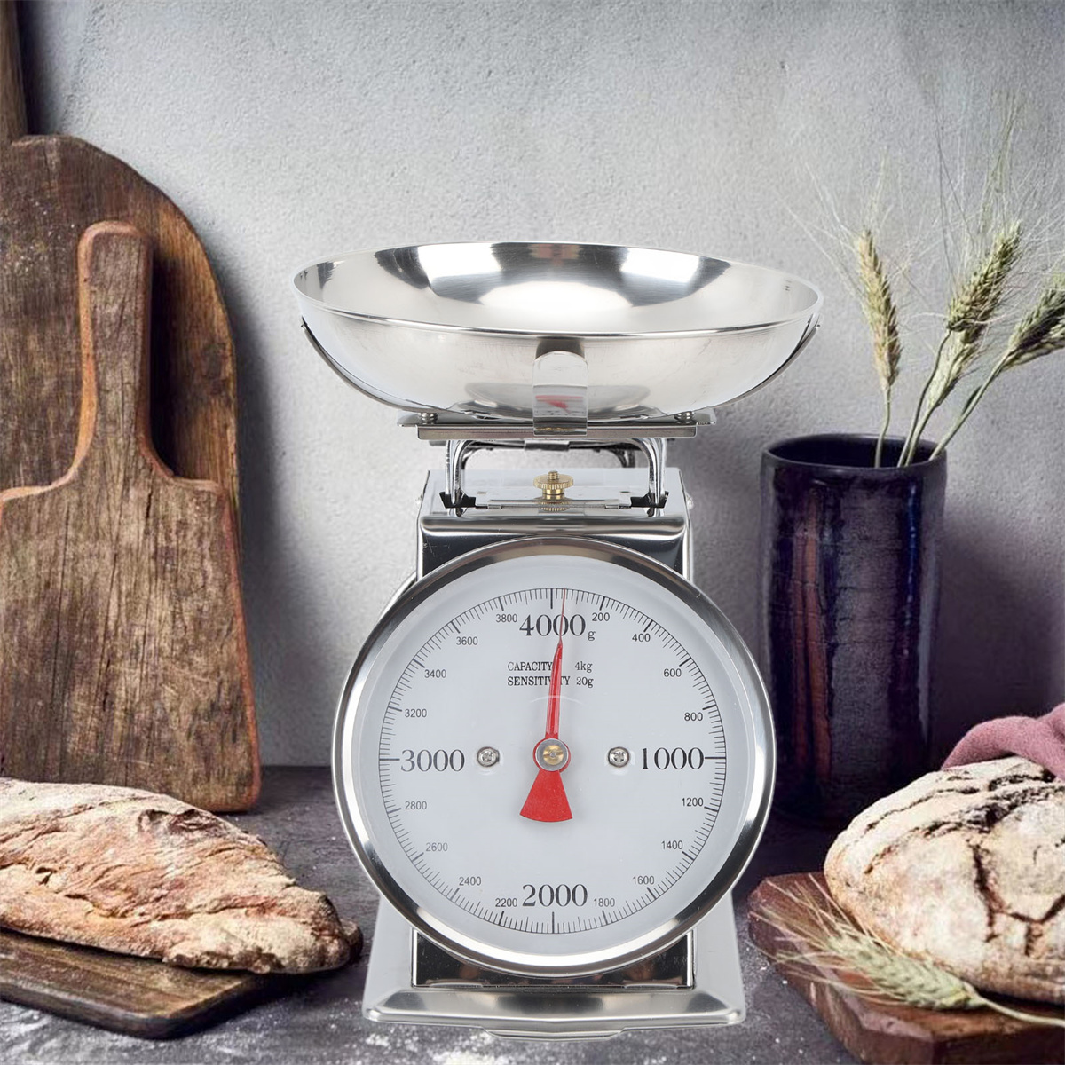 Silberne Küchenwaage mit Gewichtsanzeige. Braunes Brot und Holzbretter sind in der Nähe.