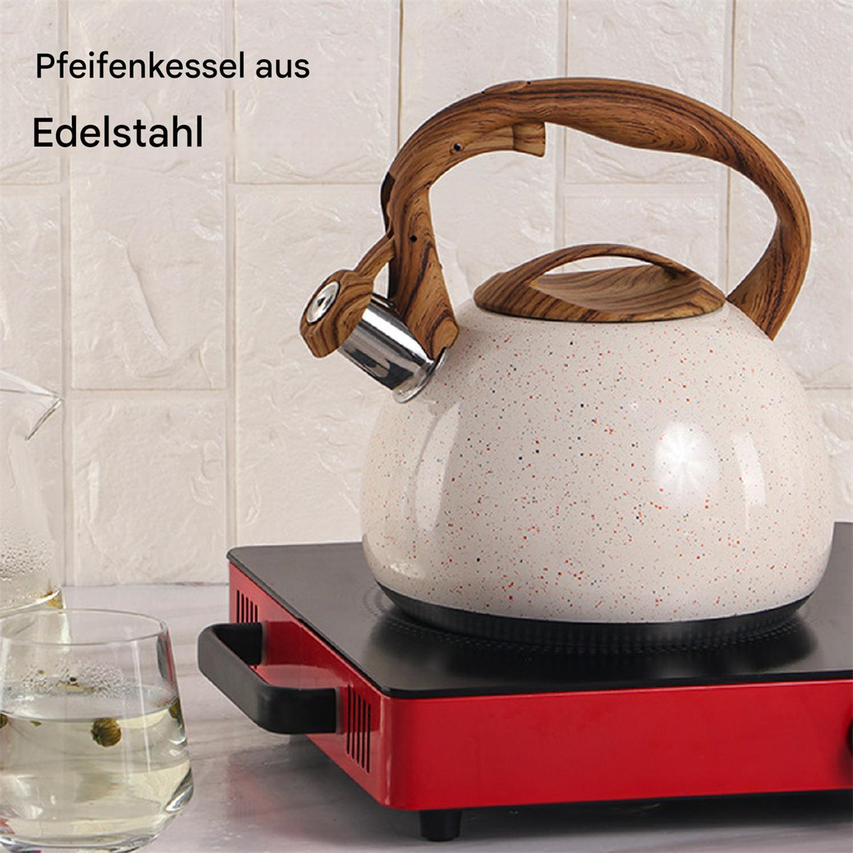 Ein weißer und gesprenkelter Wasserkocher auf einer roten Herdplatte mit Holzgriff und Deckel.