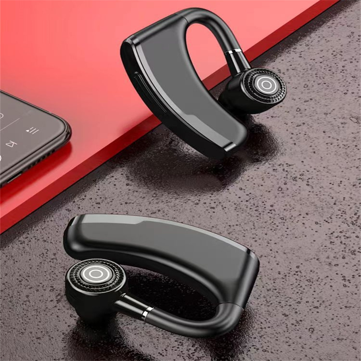 Zwei kabellose schwarze Ohrhörer-Headsets. Eines liegt auf einer roten Oberfläche, das andere in der Luft.