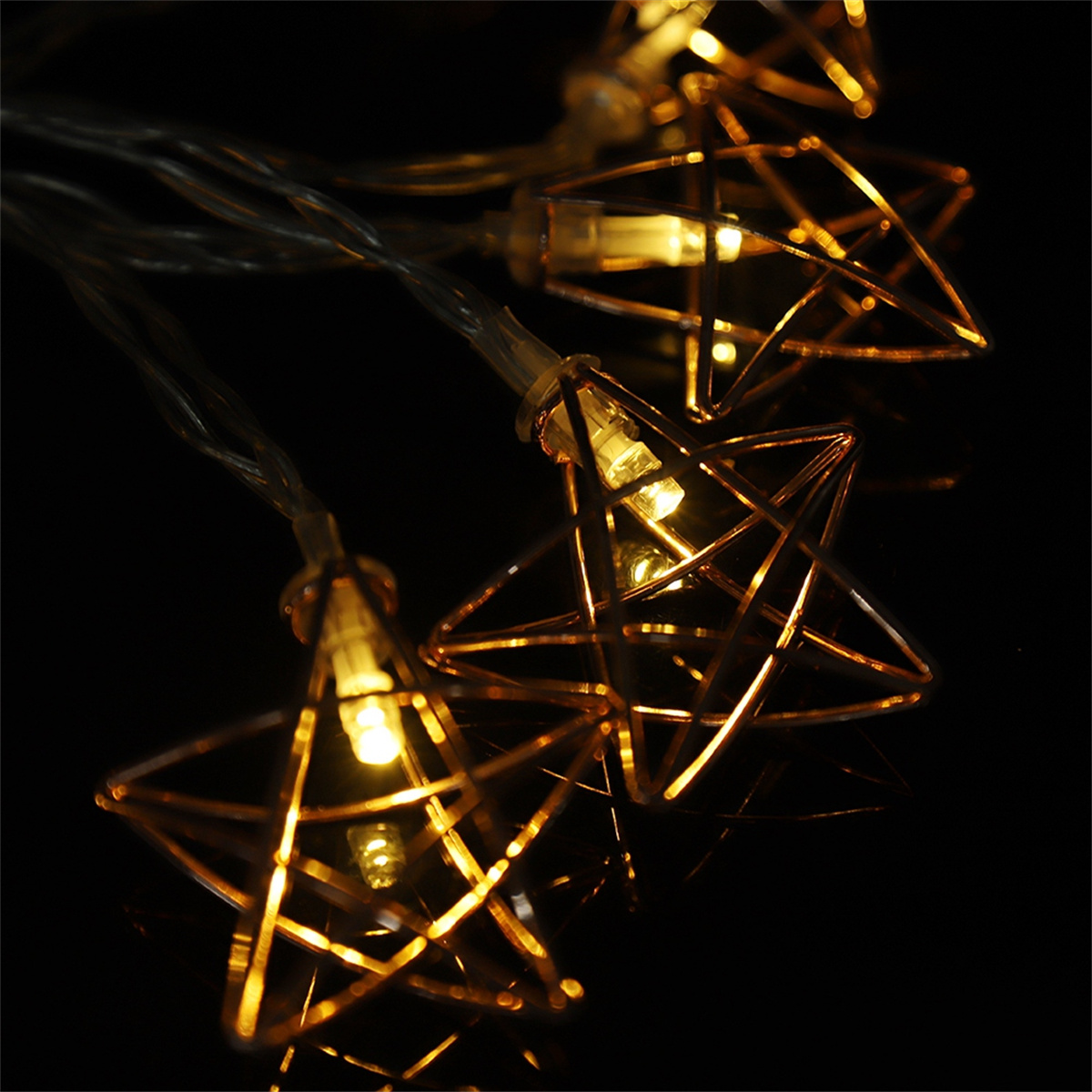 Nahaufnahme einer Lichterkette mit sternförmigen Goldlichtern, die auf dunklem Hintergrund leuchten.