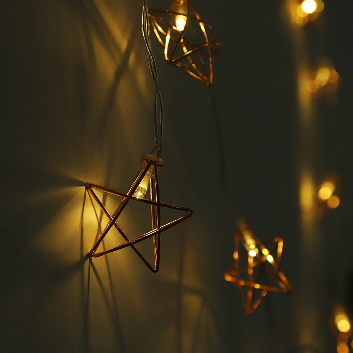 Lichterkette mit sternförmigen, kupferfarbenen Lichtern vor dunklem Hintergrund.