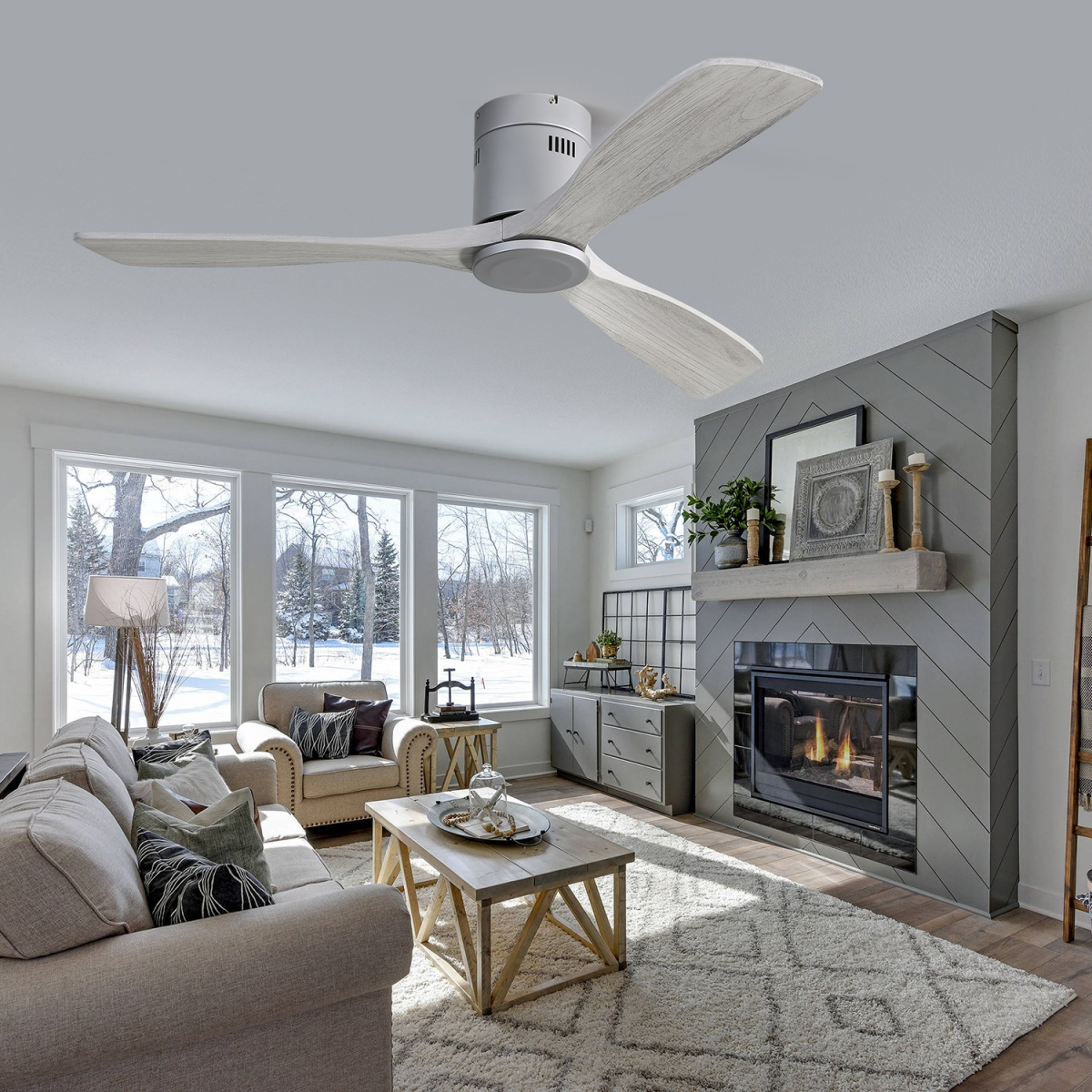 Wohnzimmer mit Deckenventilator, Kamin, Fenstern mit Blick auf eine verschneite Szene, und beige Möbeln.