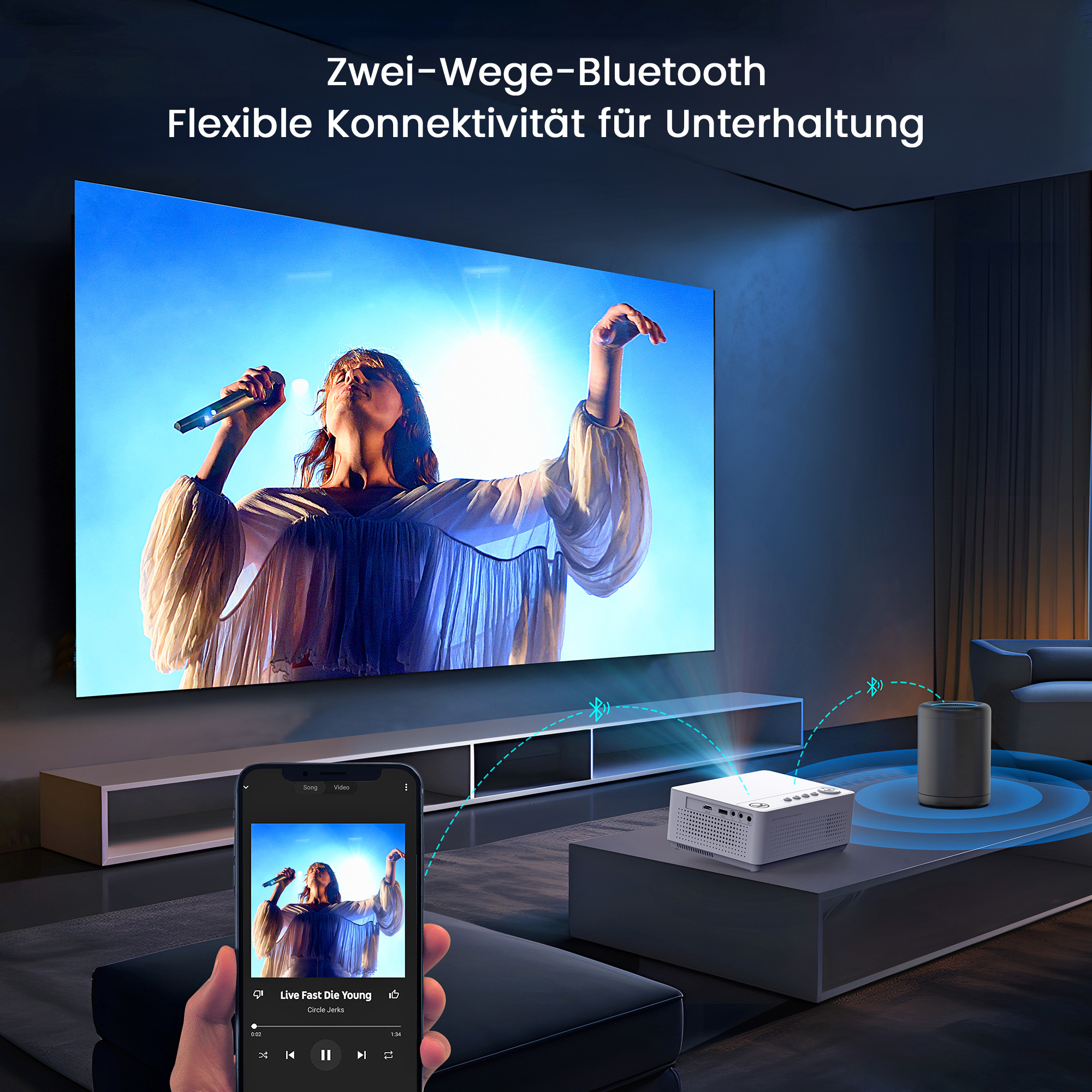 Eine Frau, die auf einer Bühne singt, wird auf eine Leinwand projiziert. Ein Telefon zeigt dasselbe Bild. Ein Projektor steht auf einem Tisch.