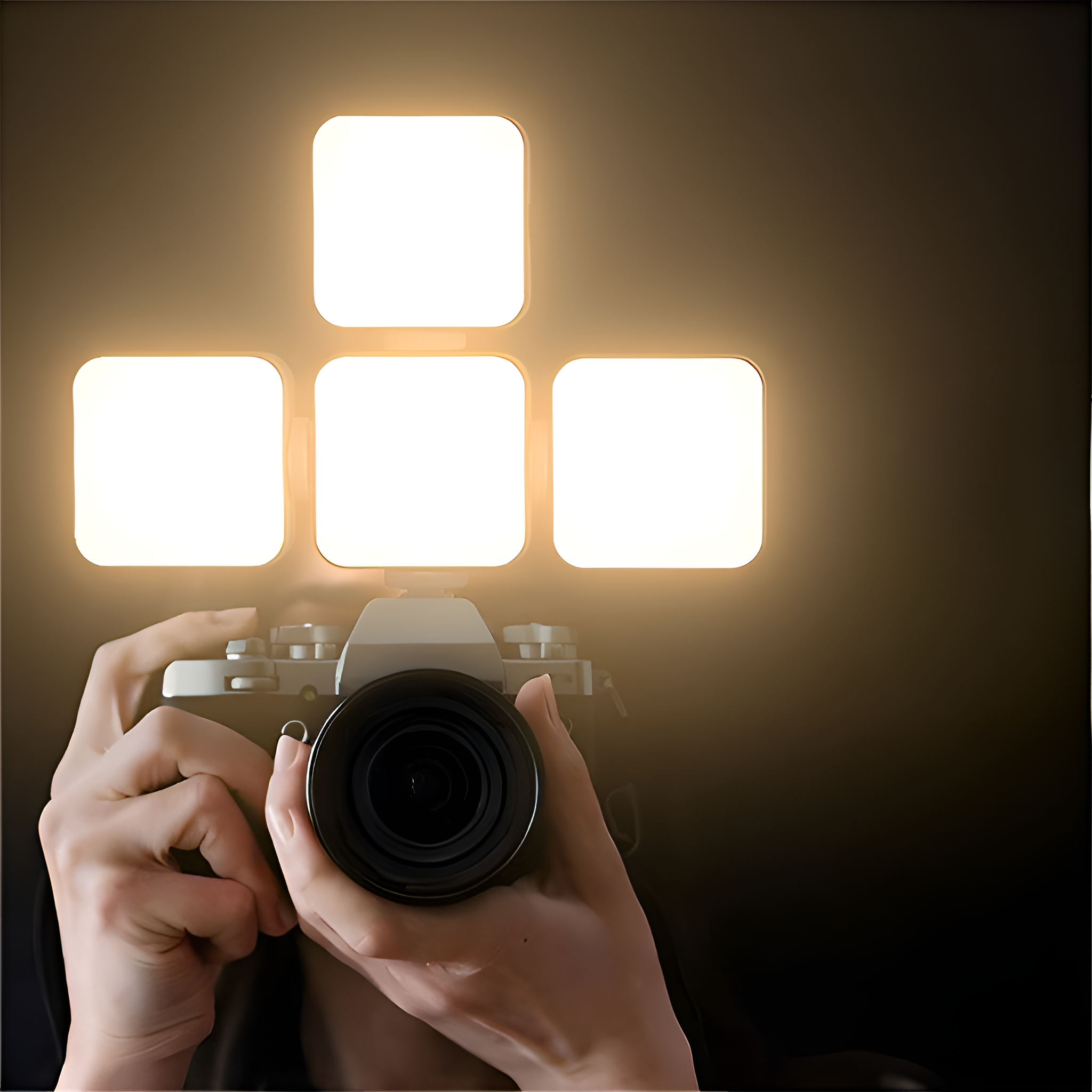 Eine Person, die eine Kamera hält, mit einer Lichtplatte darüber. Vier quadratische Lichter sind an.