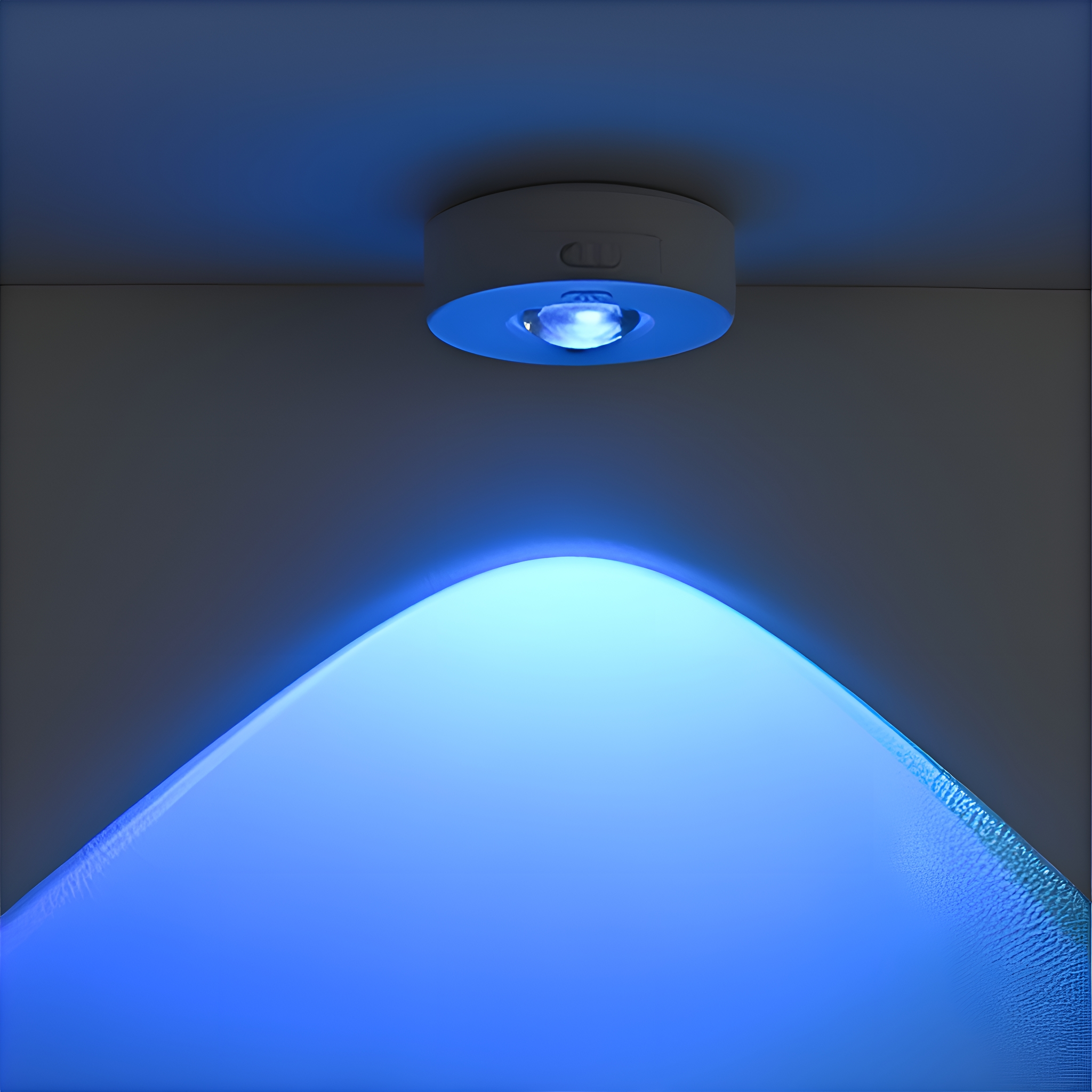 Eine weiße Deckenleuchte, die blaues Licht nach unten abstrahlt. Das Licht erzeugt einen blauen Schein an der Decke.