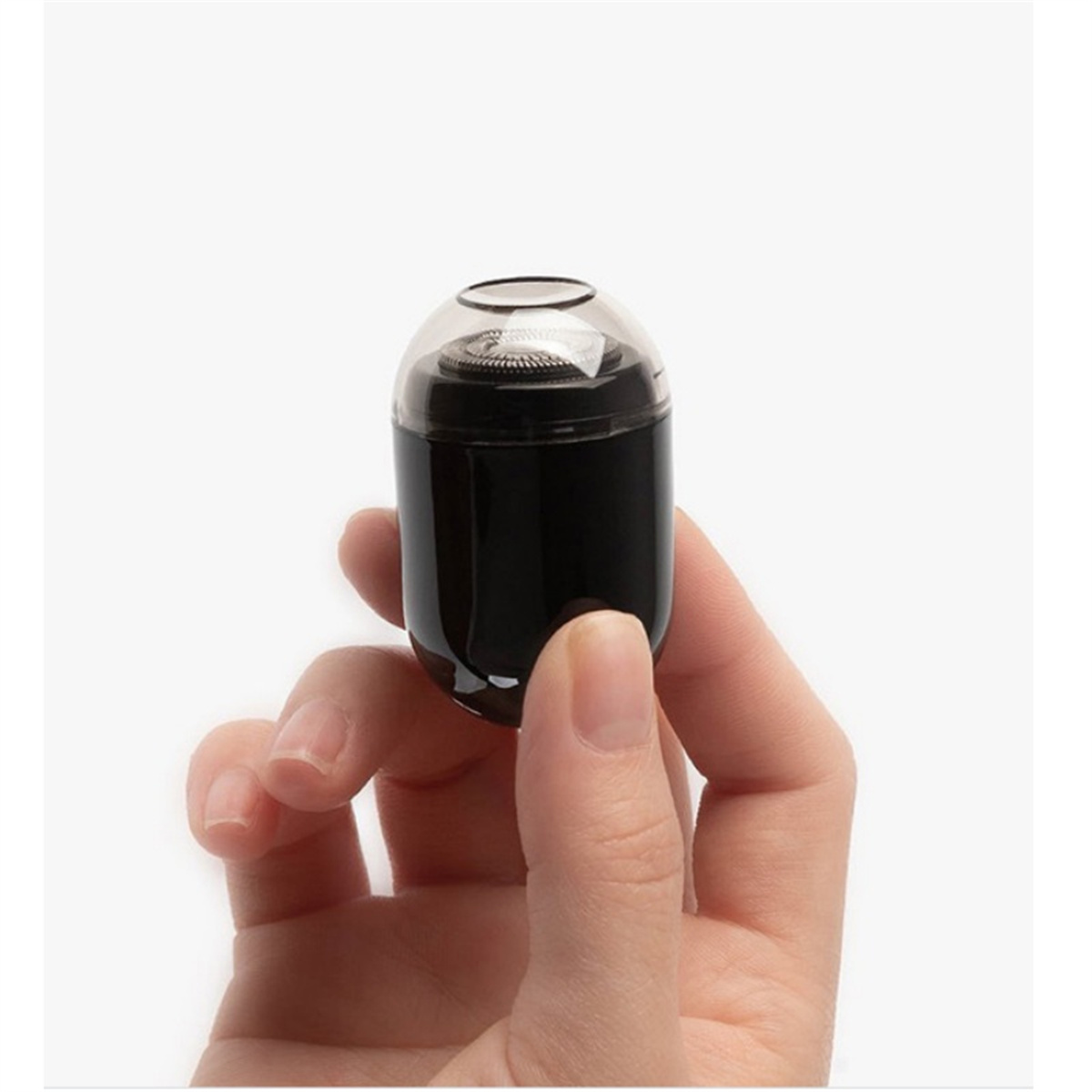 Ein schwarzer, oval geformter Elektrorasierer, der zwischen Fingern vor weißem Hintergrund gehalten wird.
